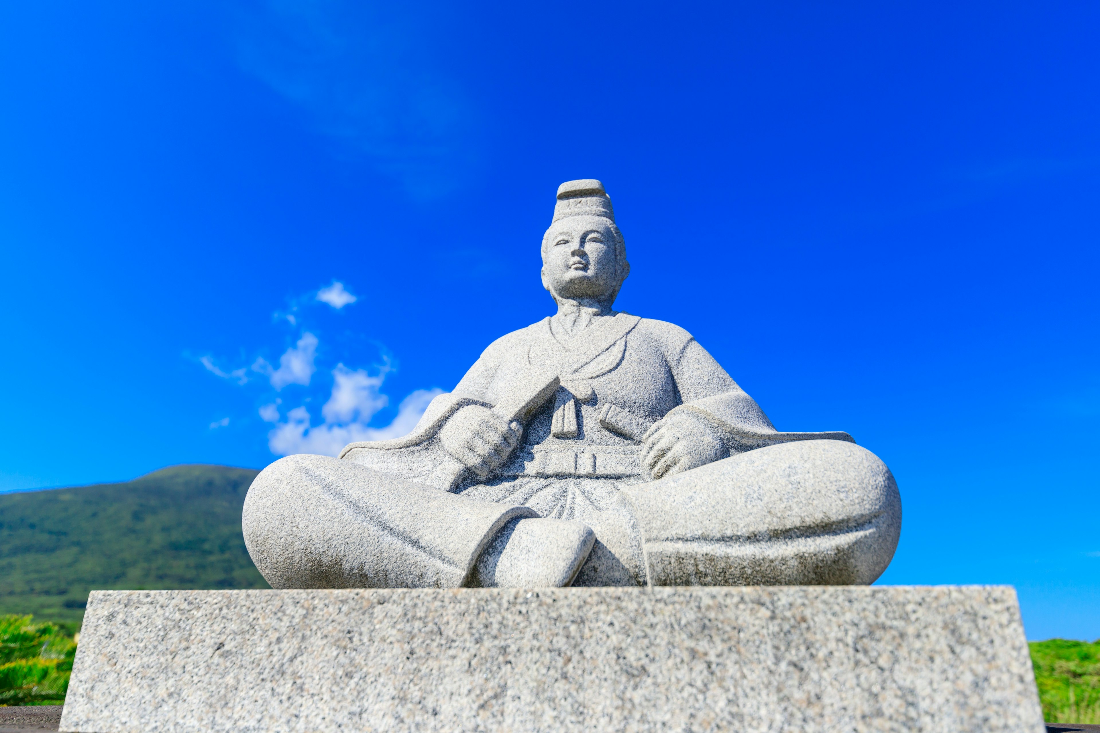 Grande statue en pierre assise sous un ciel bleu clair