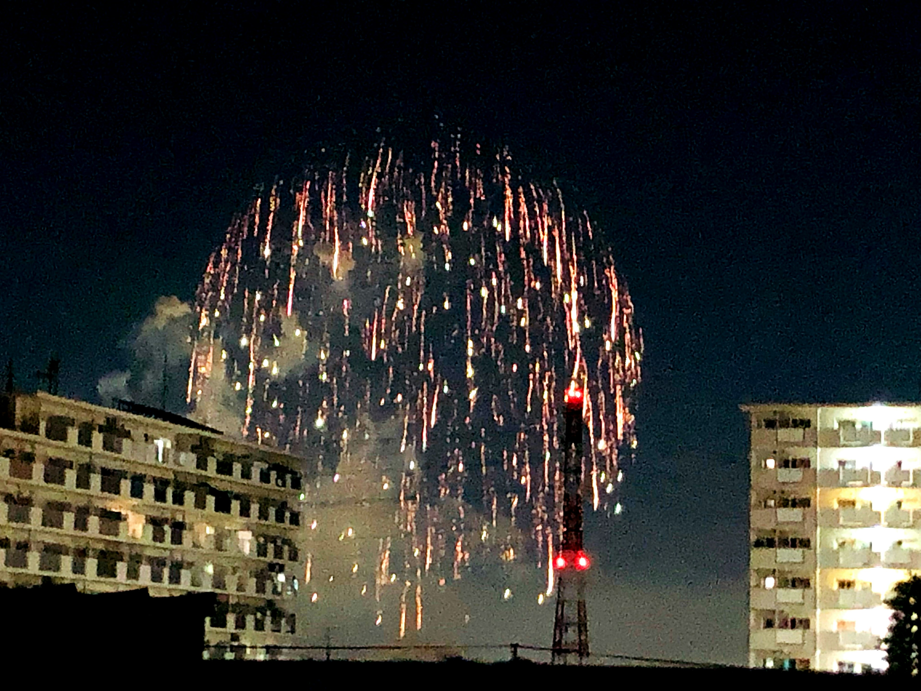 Kembang api meledak di langit malam terlihat di antara gedung tinggi