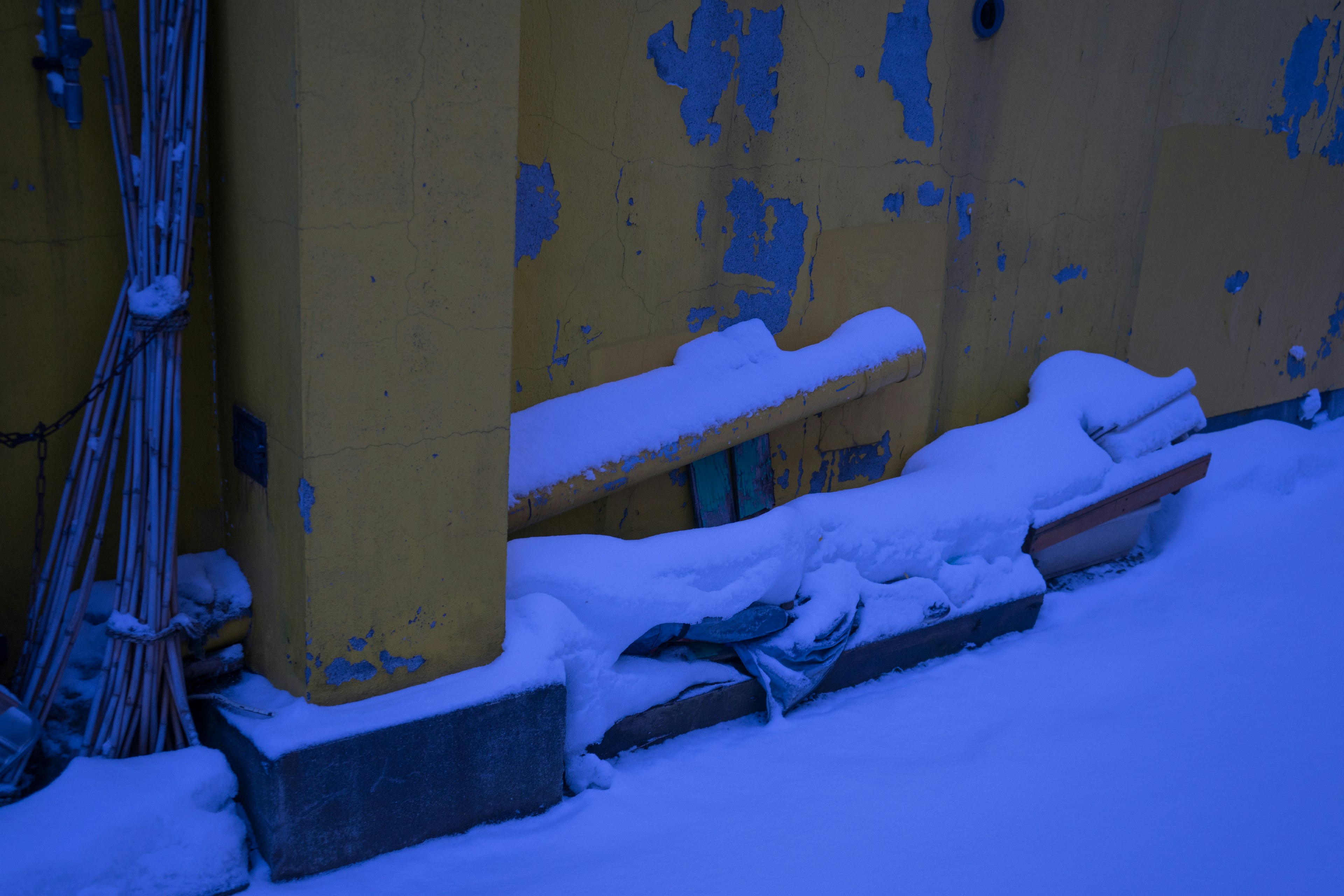 Snow-covered old wall with wooden pieces and debris