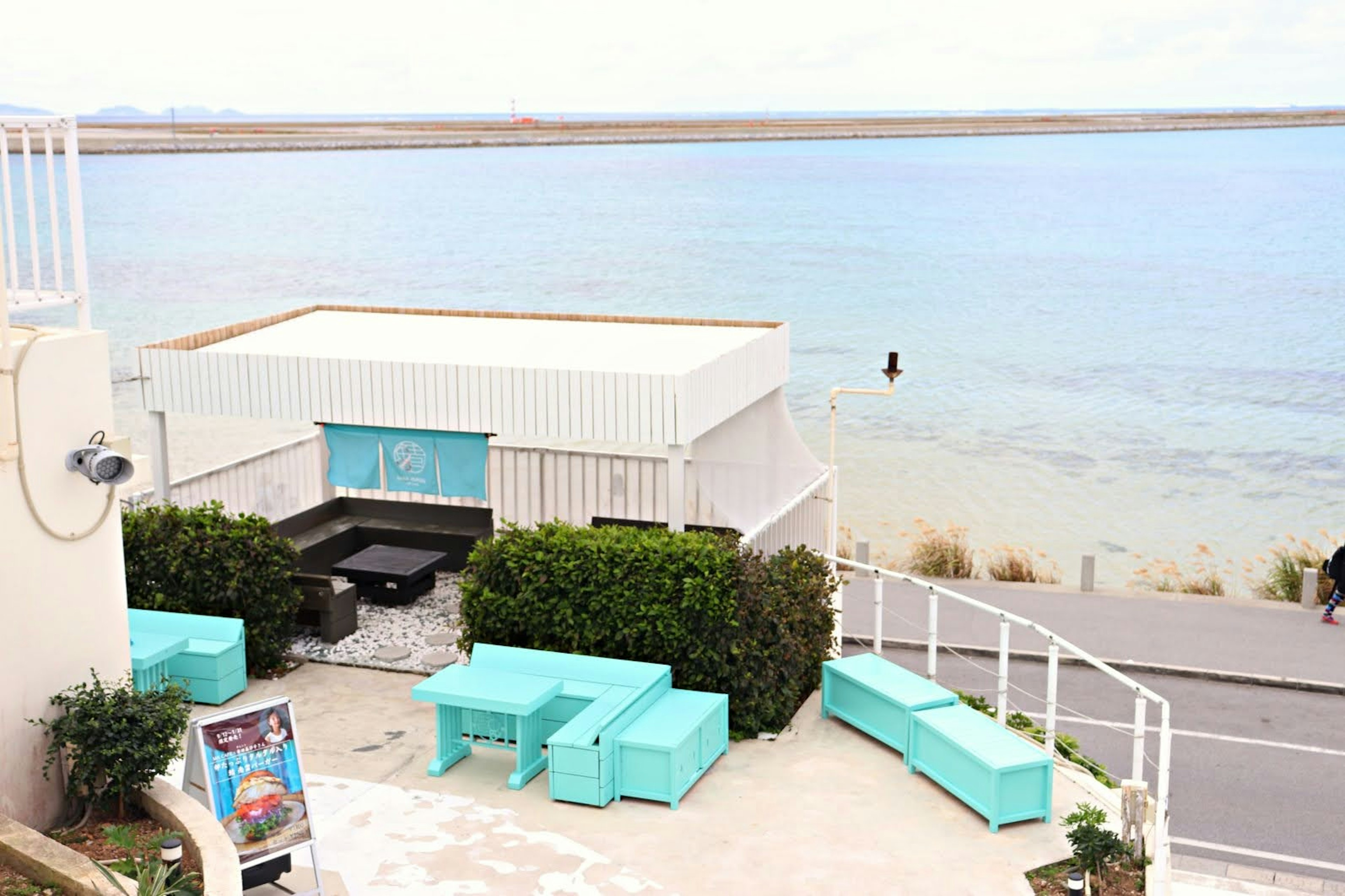 Kafe tepi pantai dengan furnitur biru dan pemandangan laut