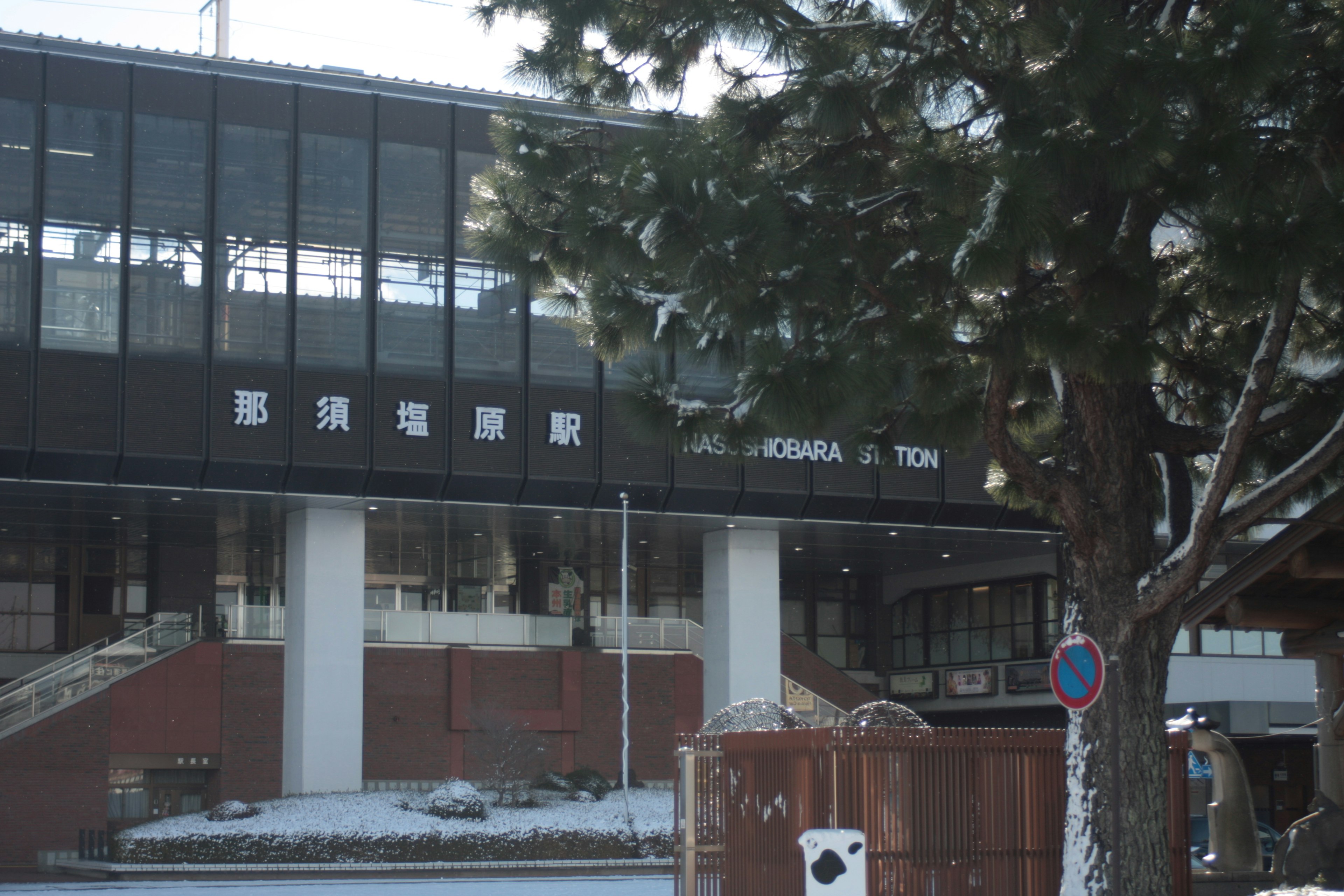 Vista exterior de una estación de tren cubierta de nieve con árboles alrededor