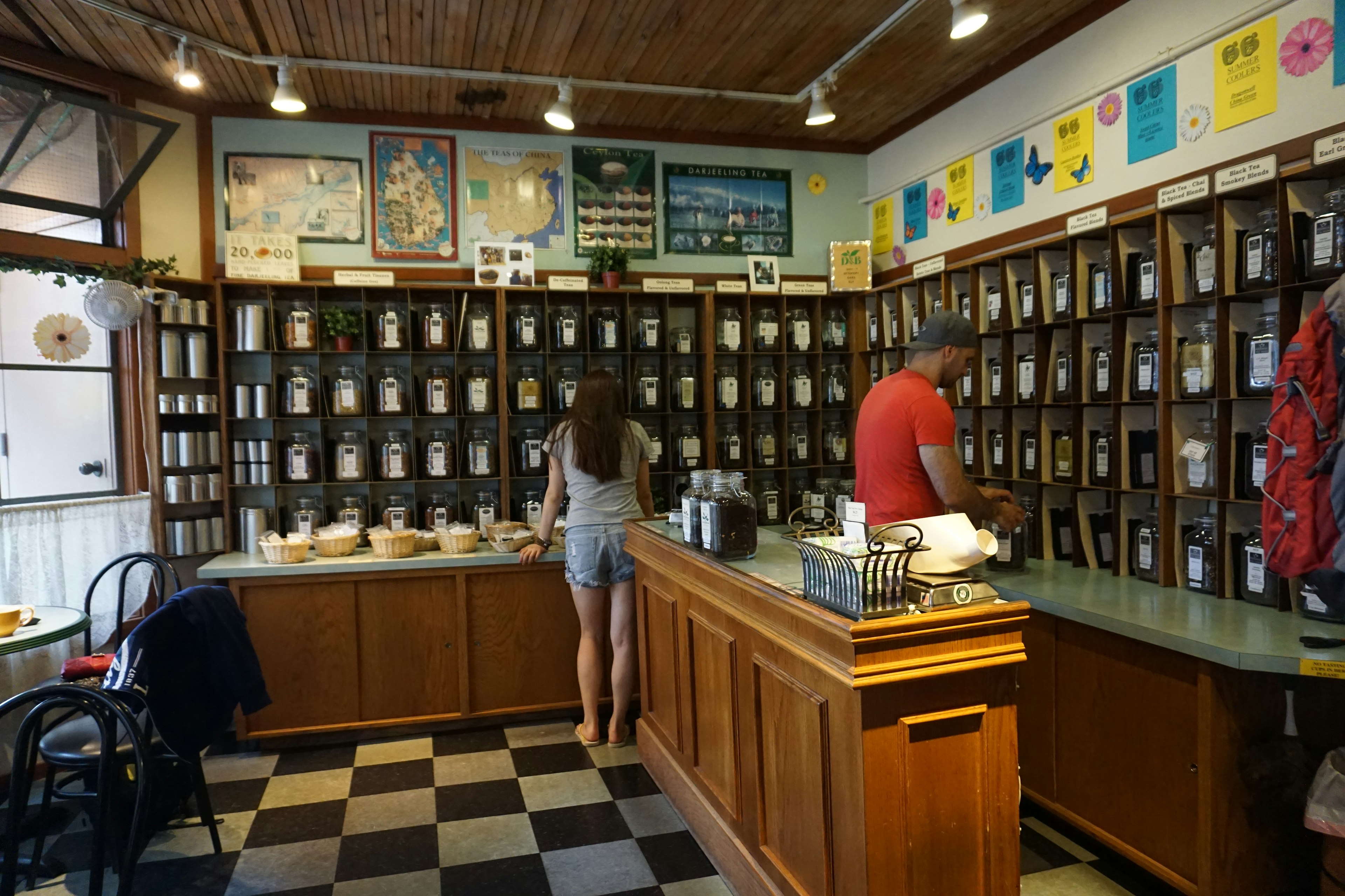 The interior features various tea leaves displayed with customers selecting them