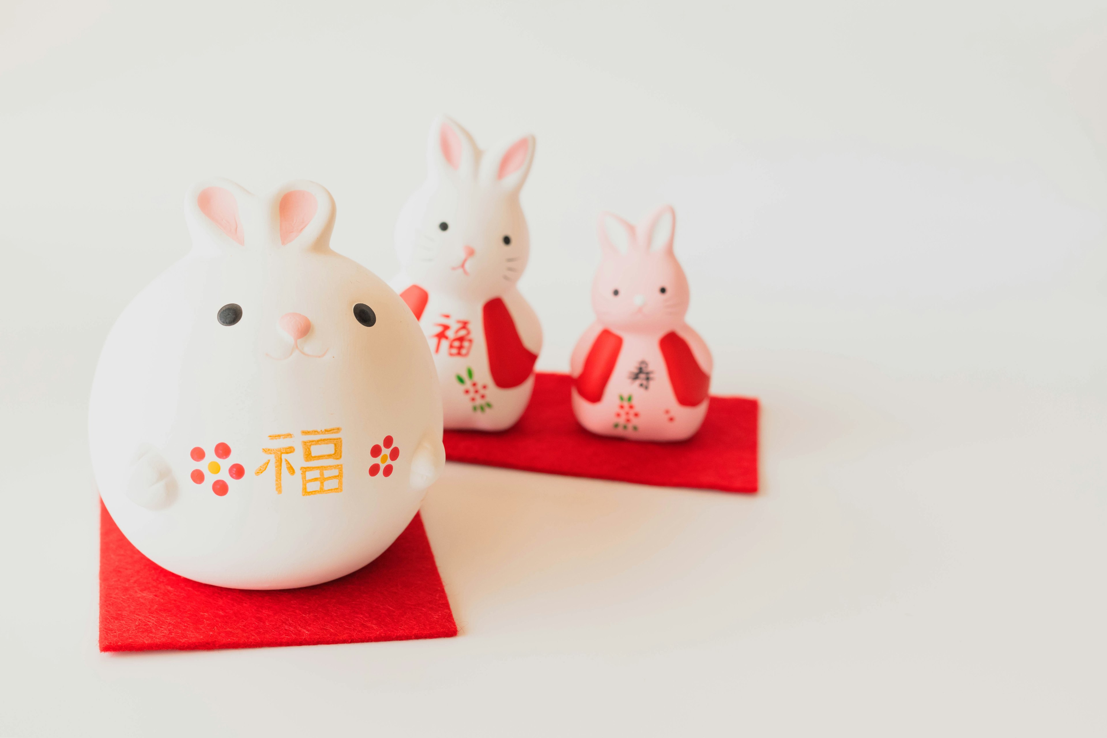 Decorative white rabbit figurine with two pink rabbits on red mats