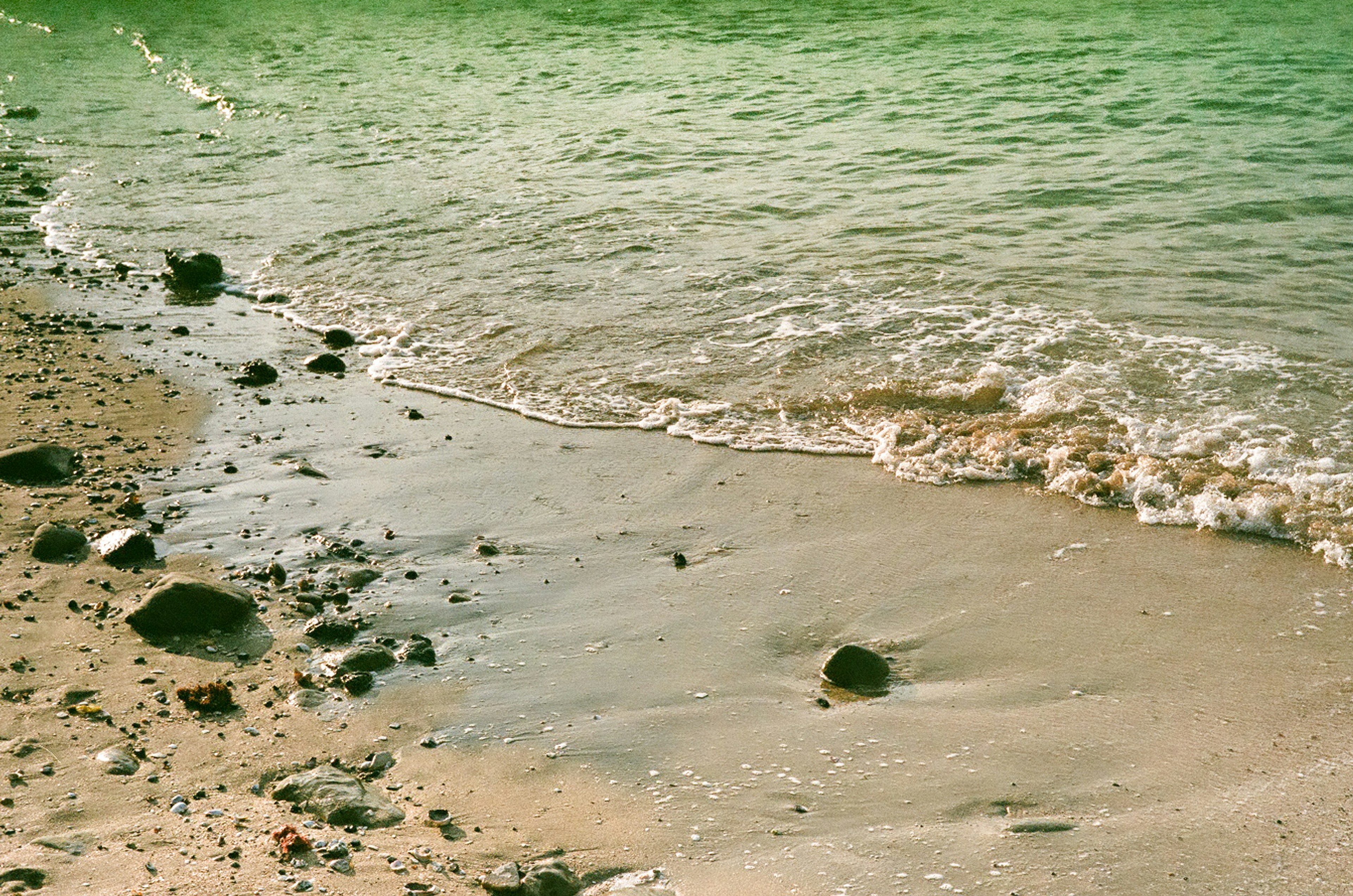 Garis pantai dengan ombak lembut dan kerikil