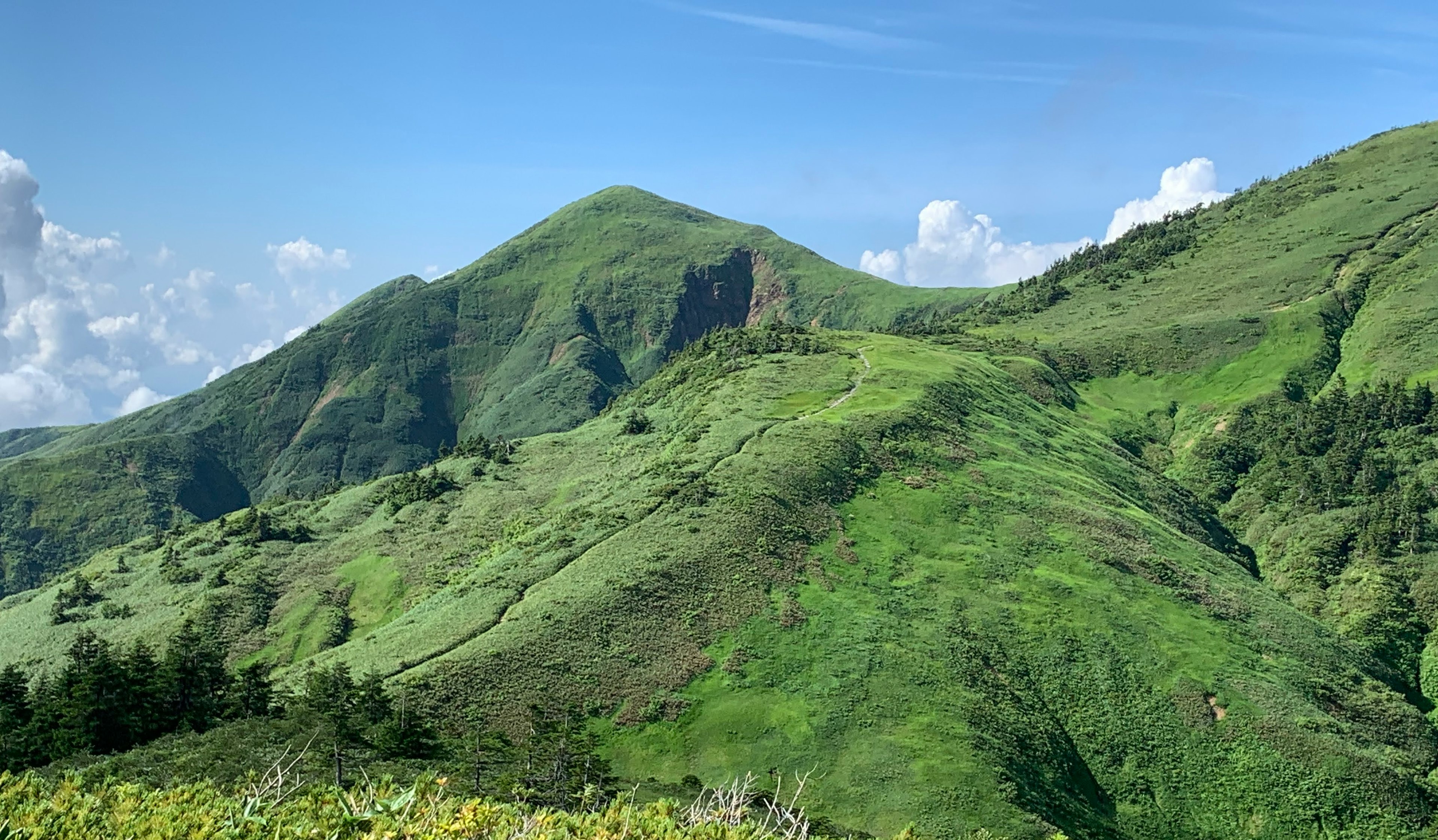 Paisaje montañoso verde bajo un cielo azul