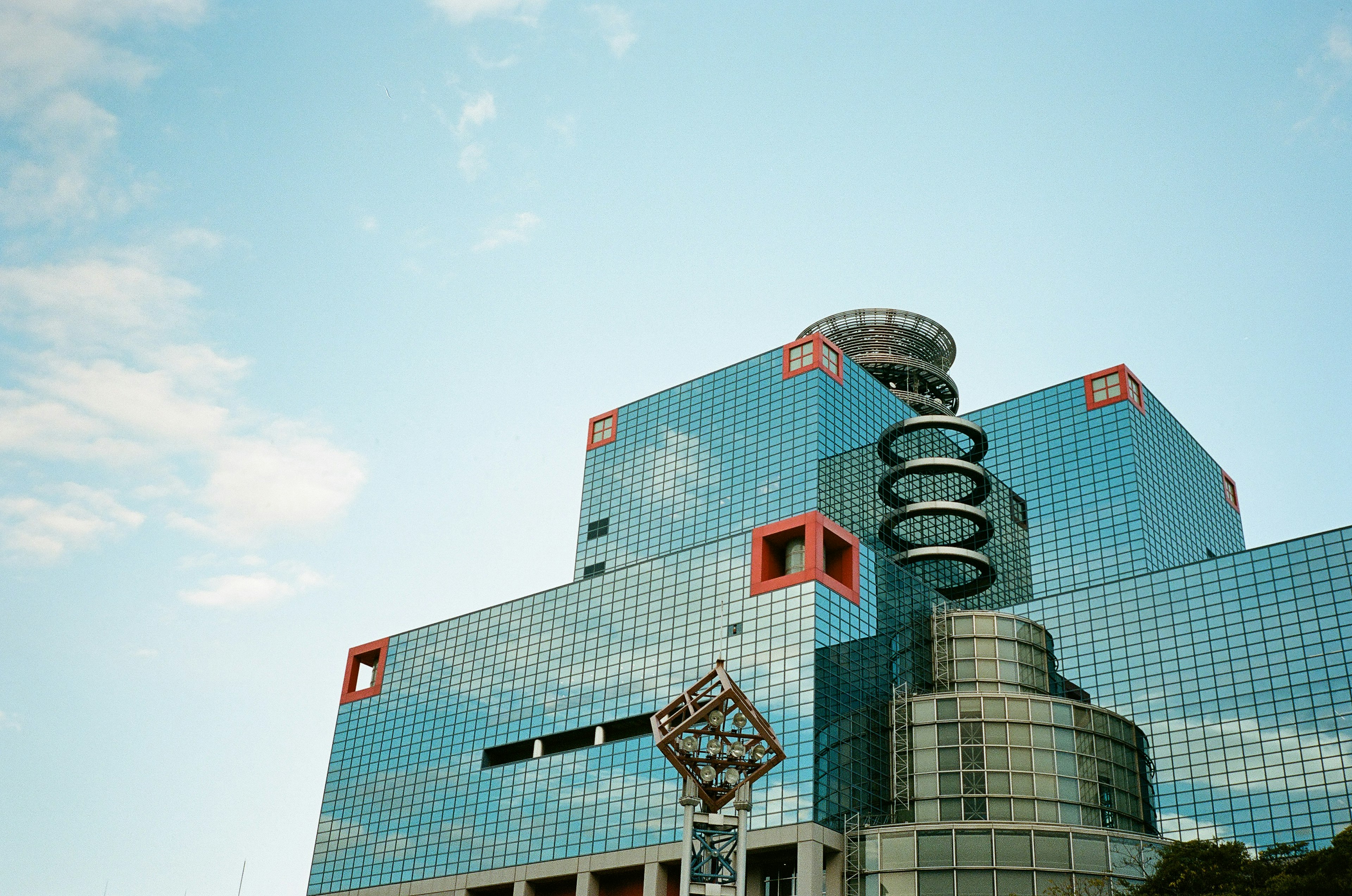 Modern glass building with unique clock under blue sky