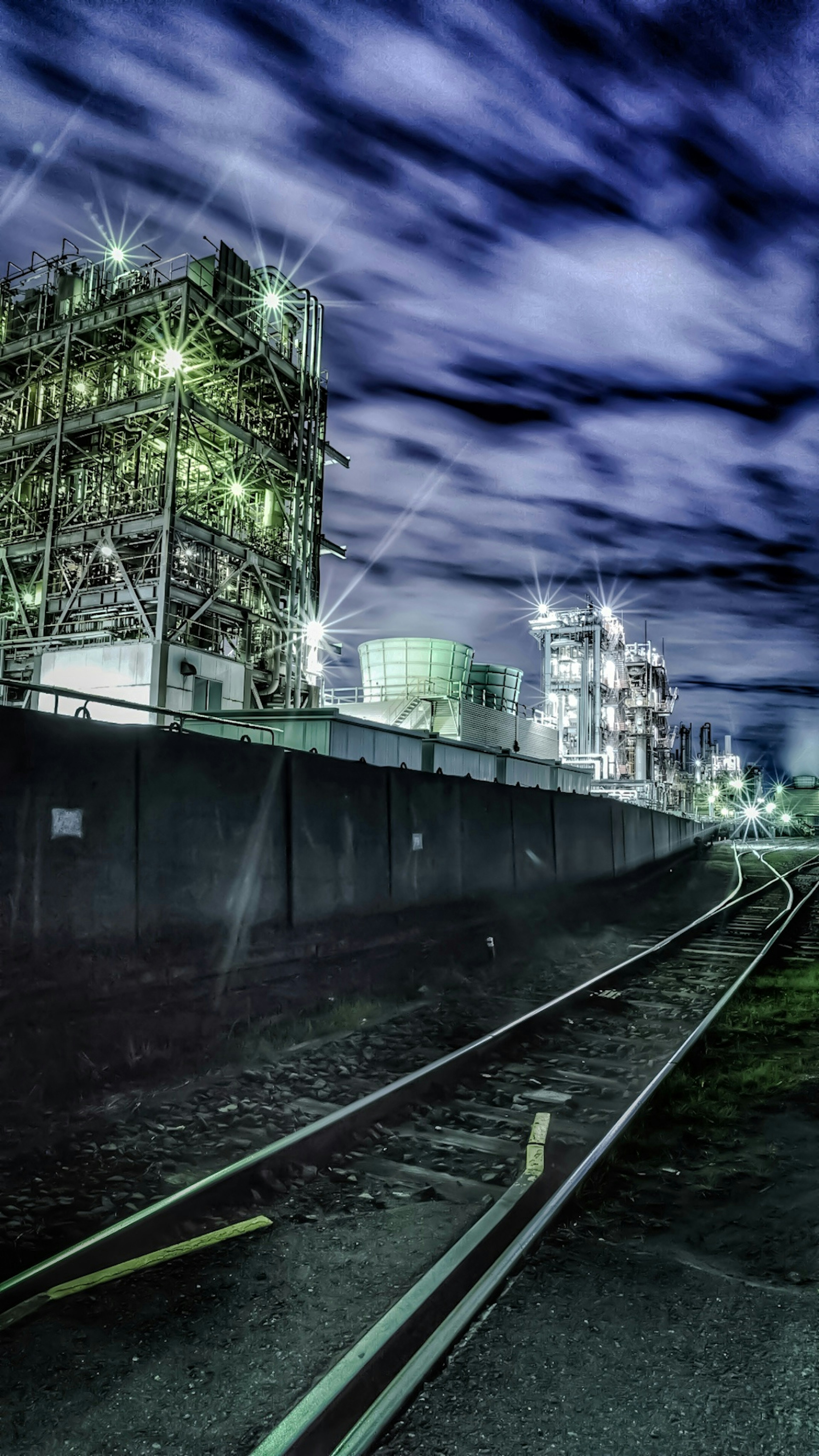 Vista notturna con strutture industriali e binari ferroviari