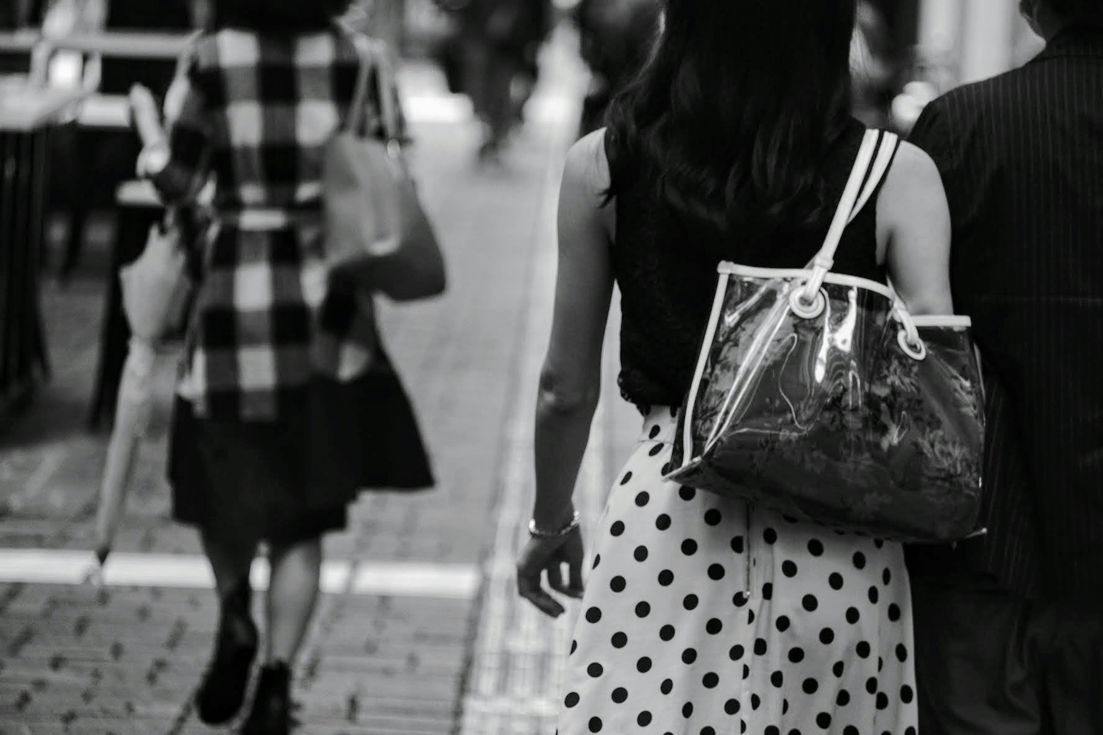 Una donna in un vestito a pois che cammina per una strada con un'altra figura sullo sfondo