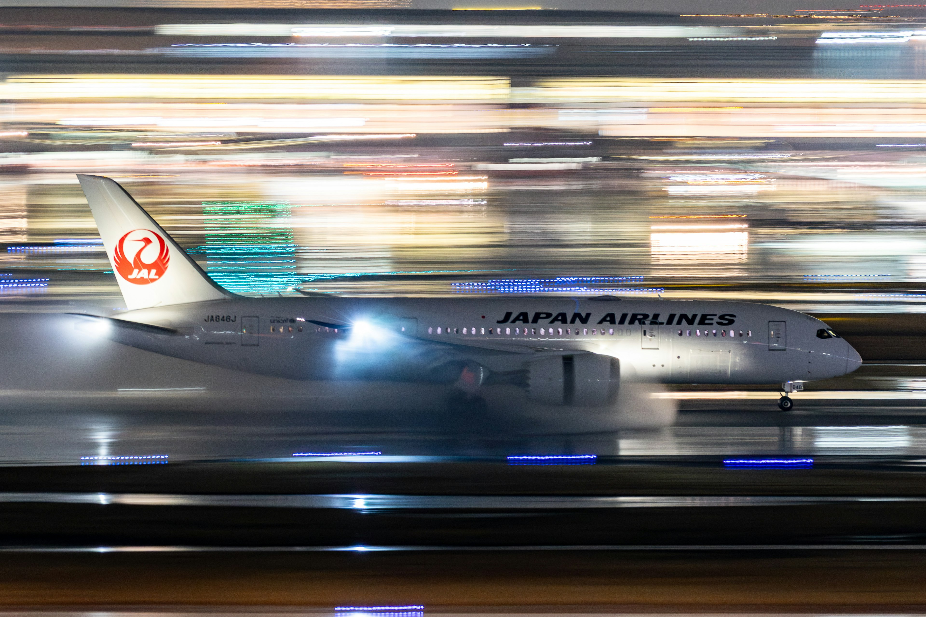 Aereo Japan Airlines che taxi sulla pista di notte con luci sfocate