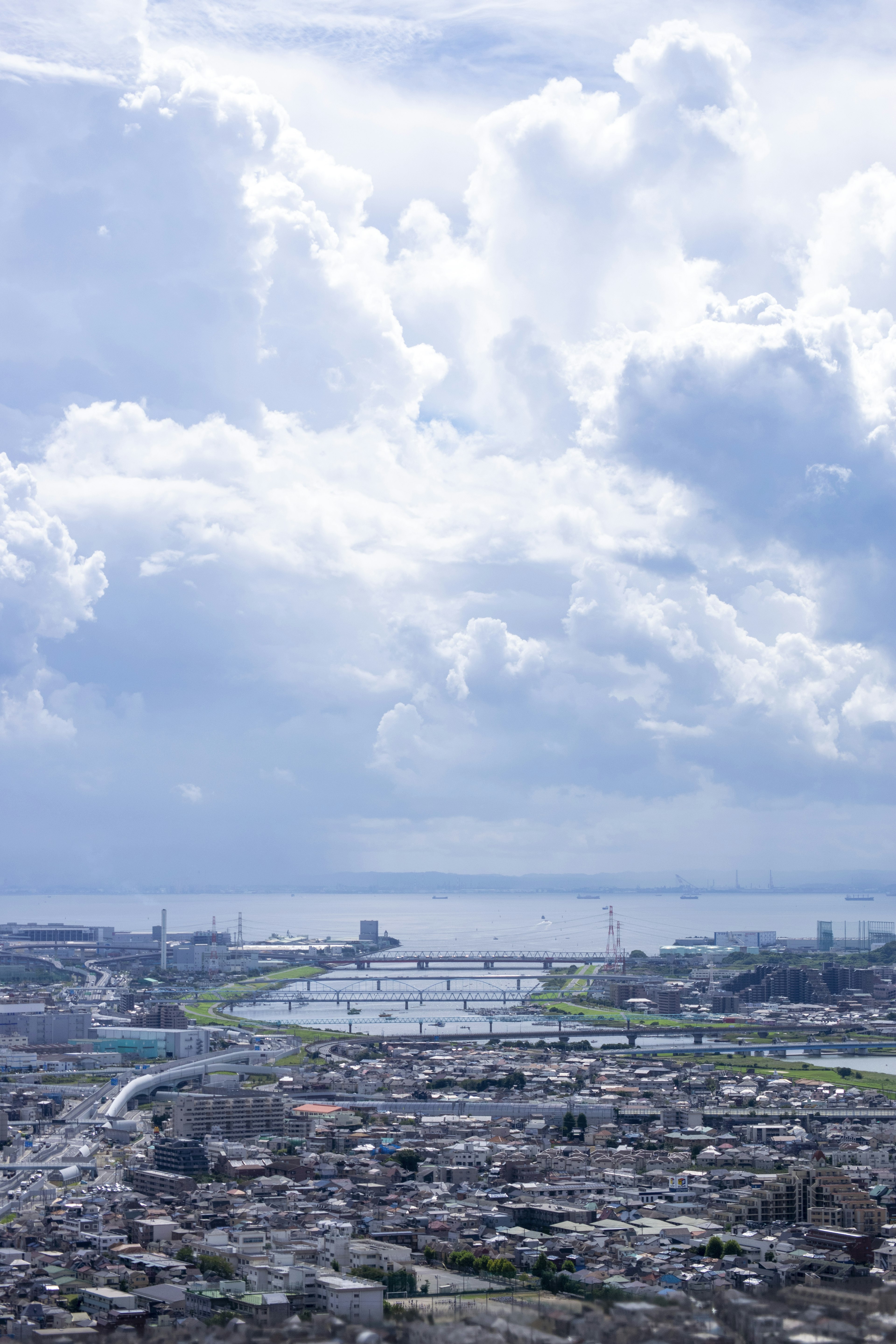 青い空と白い雲が広がる都市の風景 近くに川と港が見える