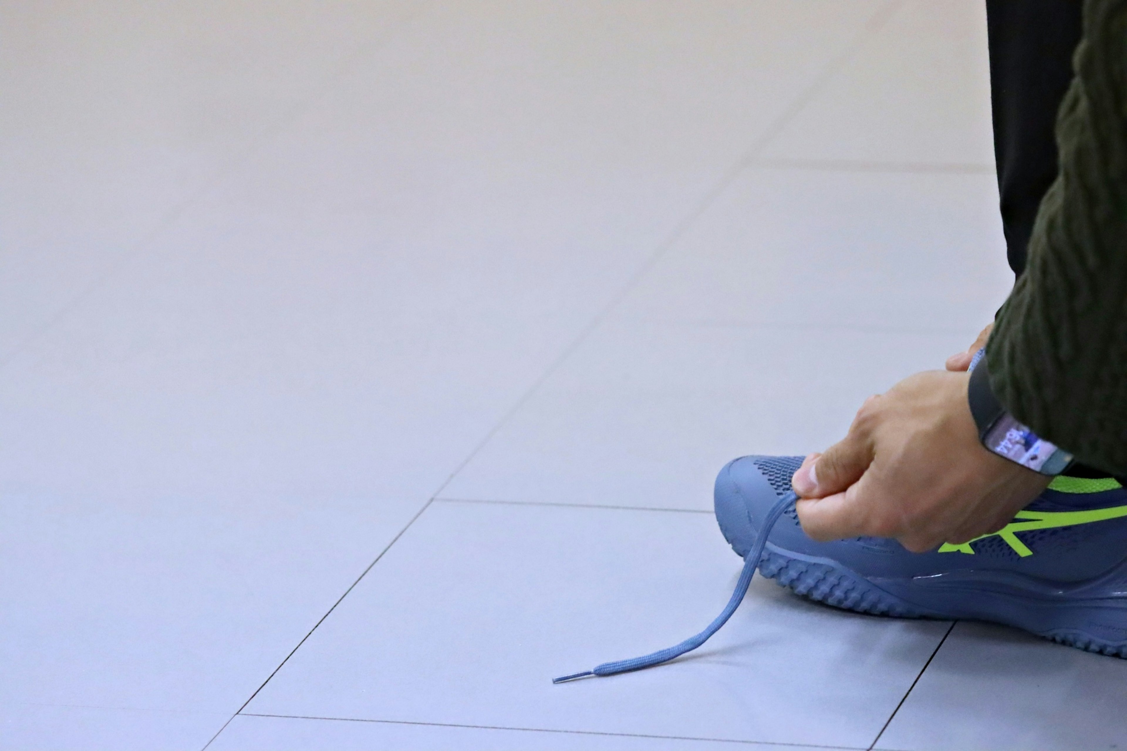 Person tying shoelaces on blue sneaker