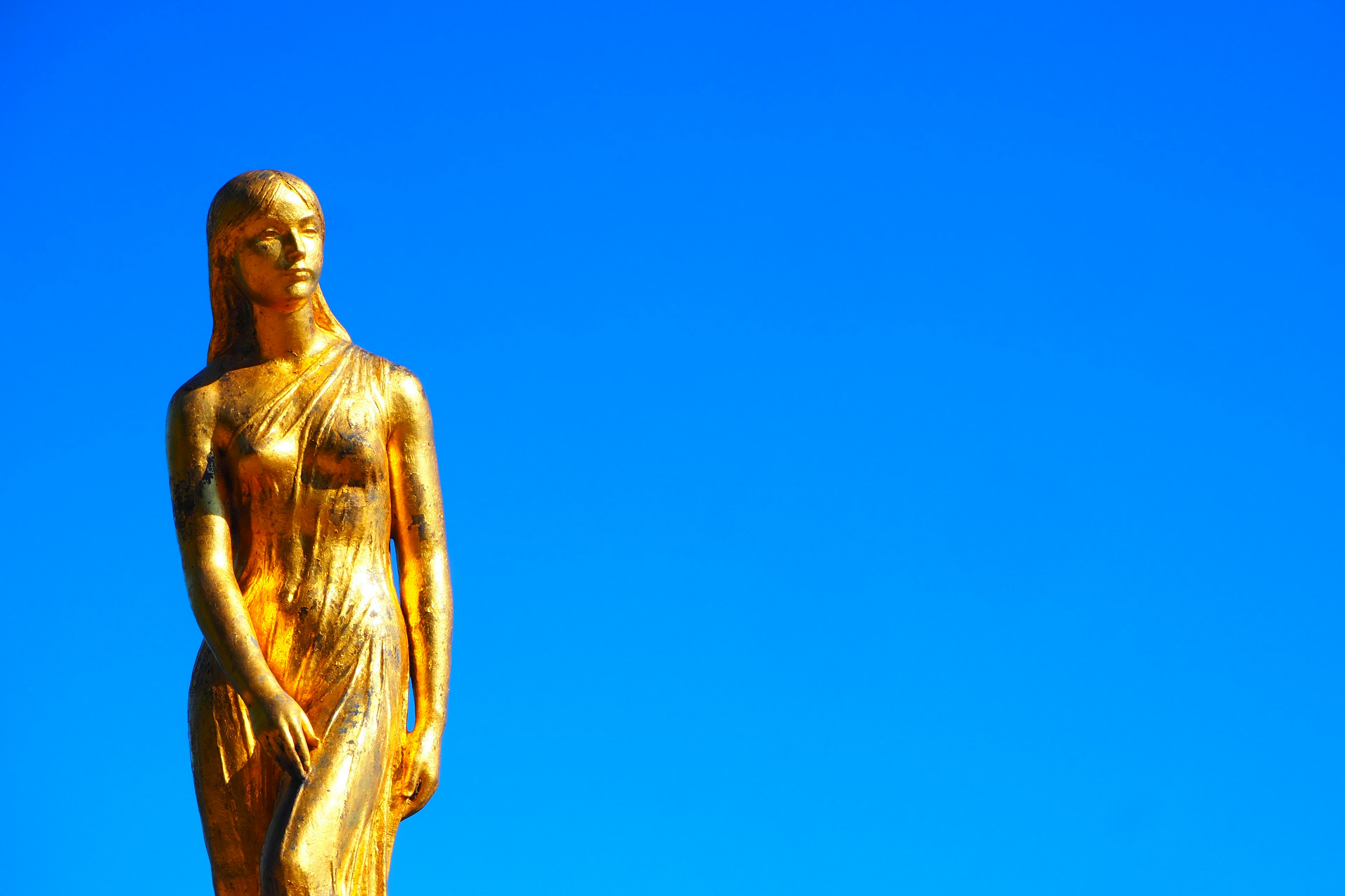 Golden statue standing under a blue sky