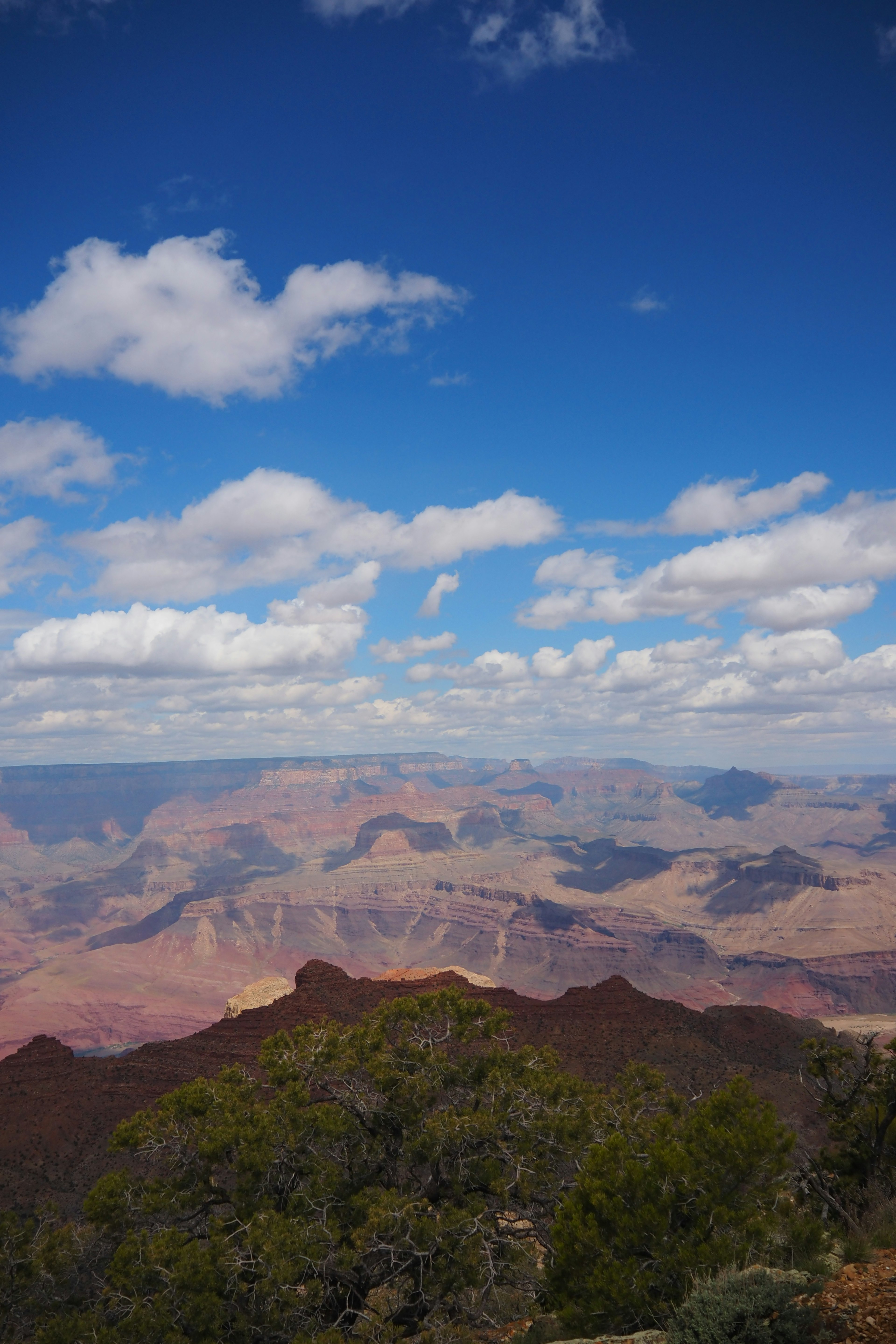 Khung cảnh rộng lớn của Grand Canyon với bầu trời xanh và mây trắng