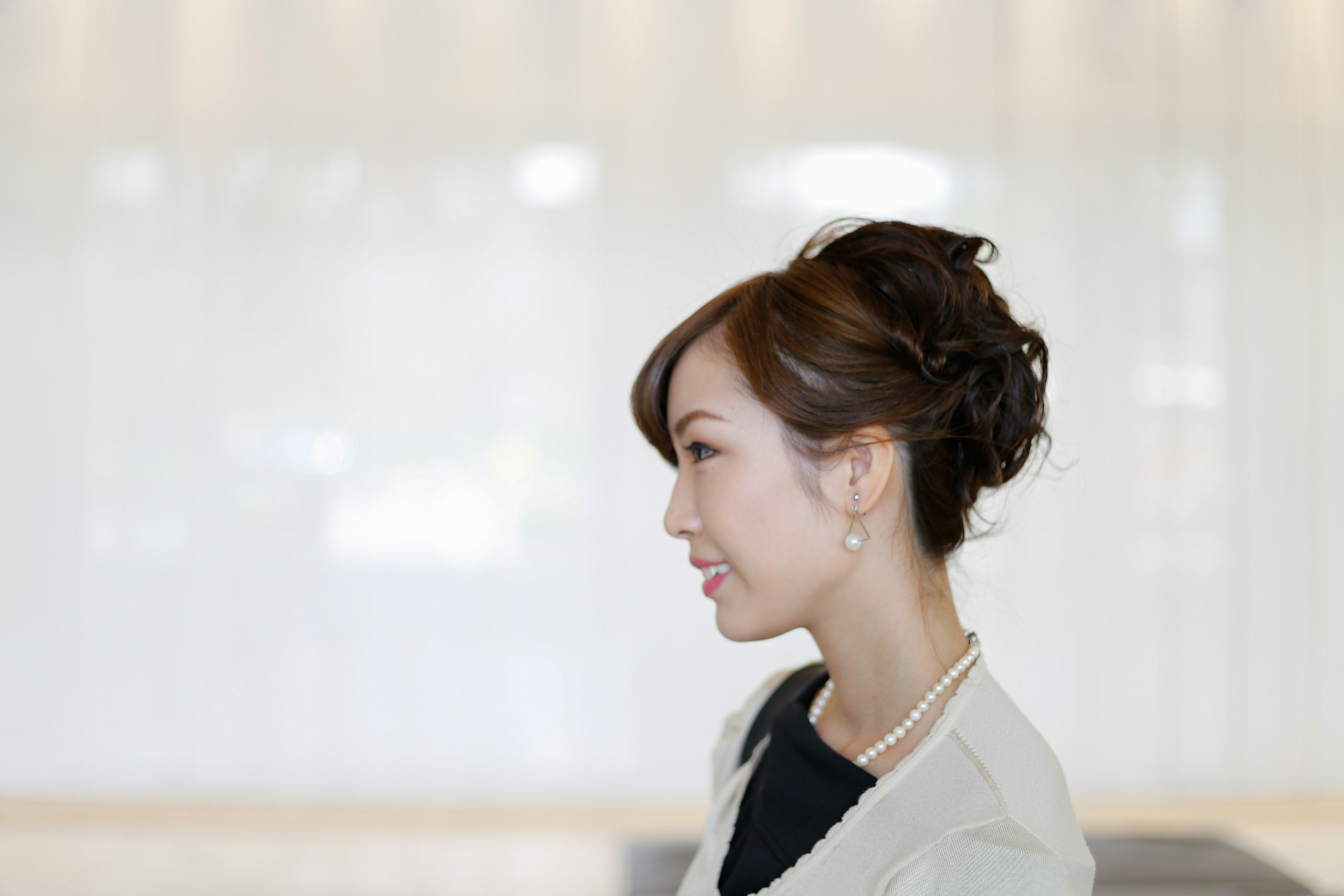 A woman smiling in profile with a blurred light-colored background