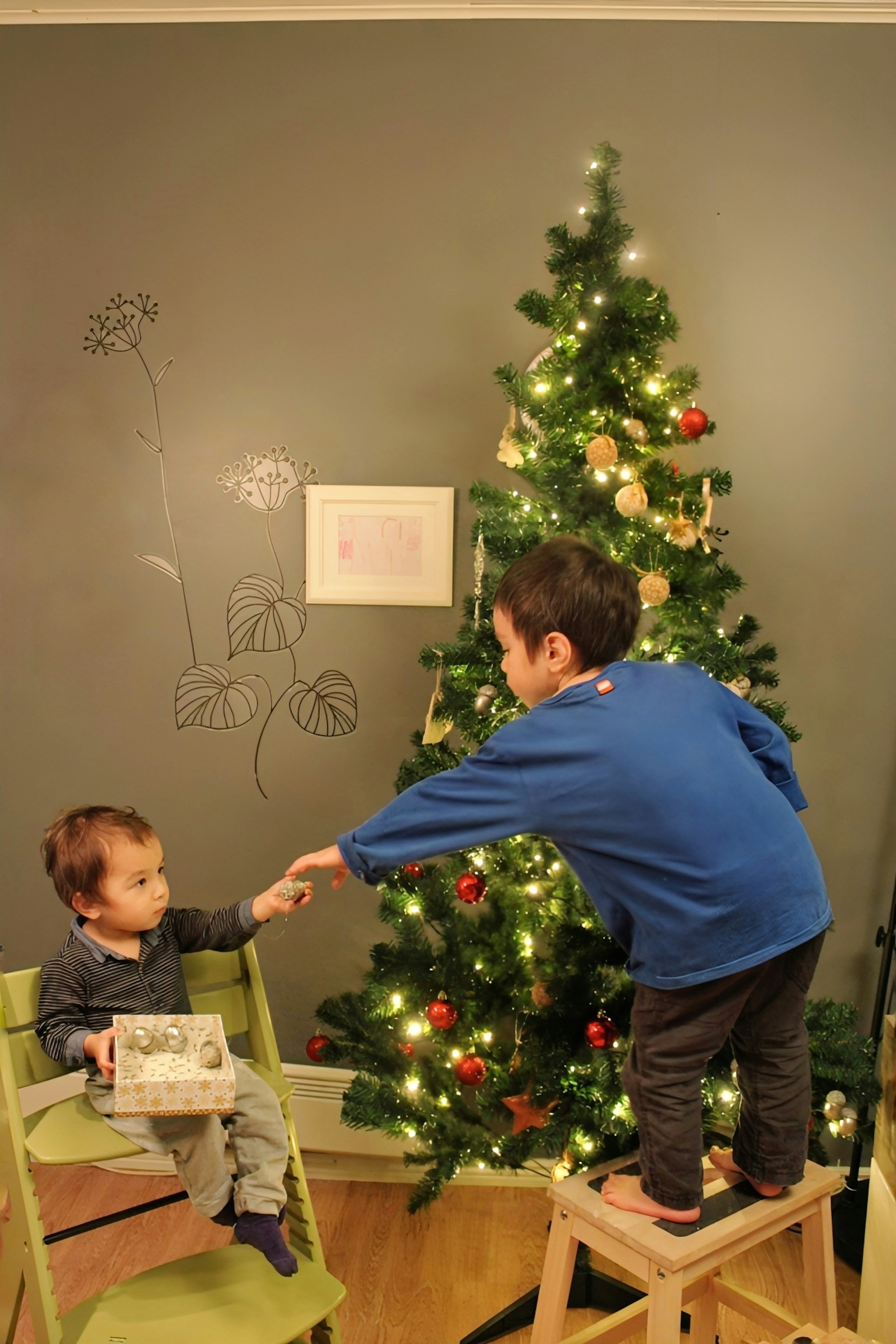 Deux enfants jouant devant un sapin de Noël