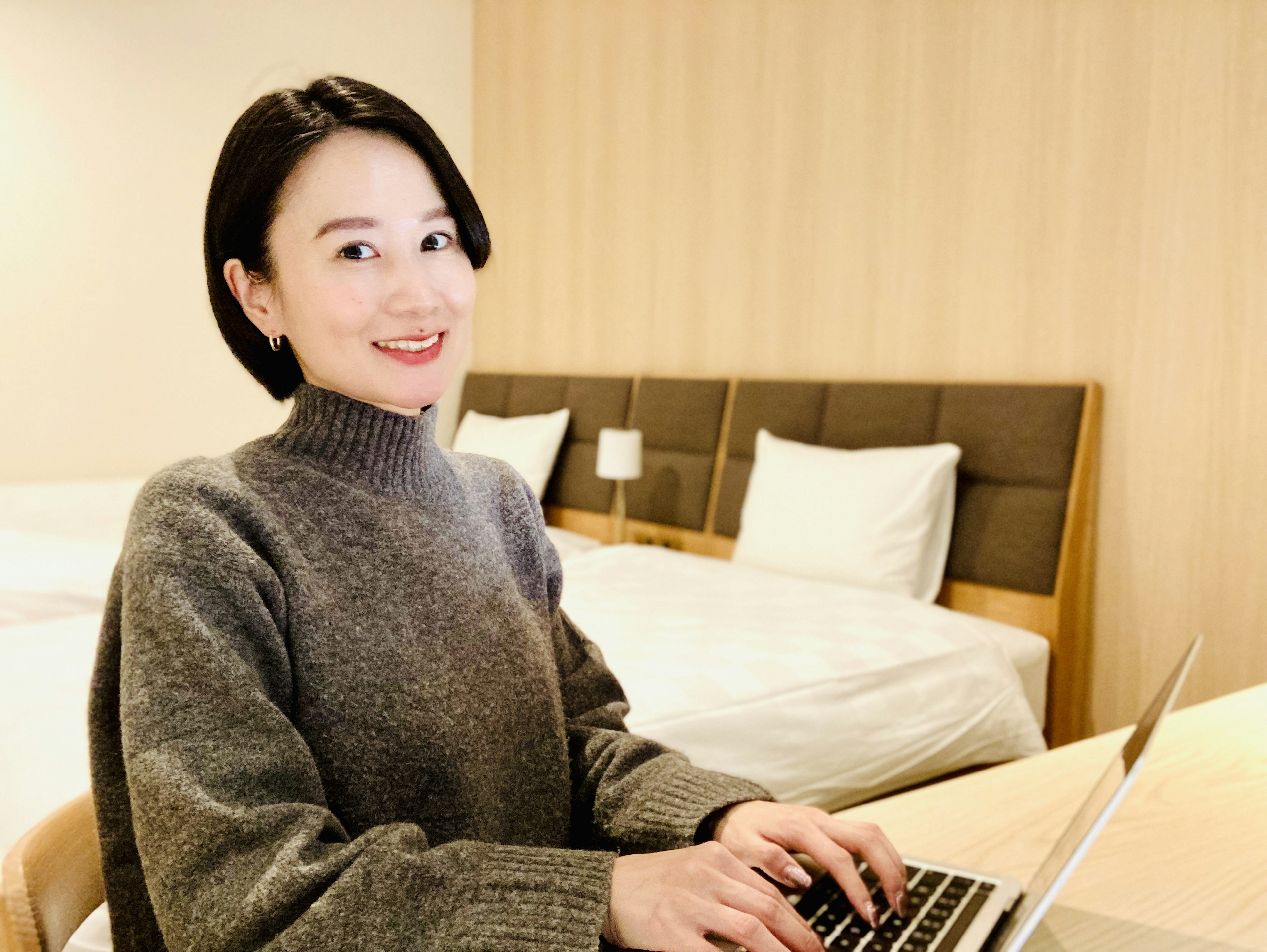 Woman smiling while using a laptop in a hotel room