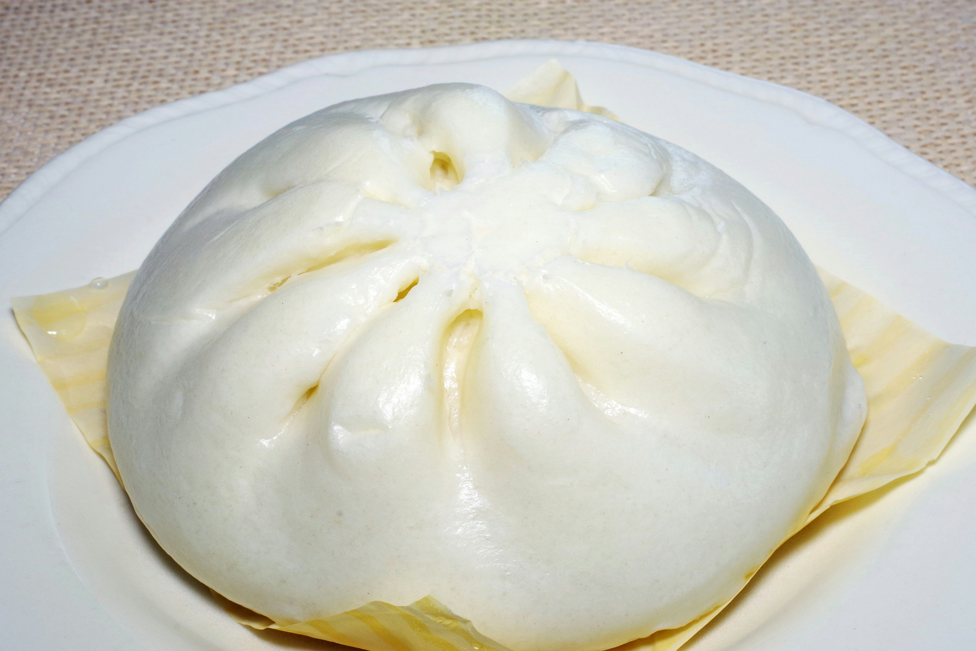 A white steamed bun placed on a plate