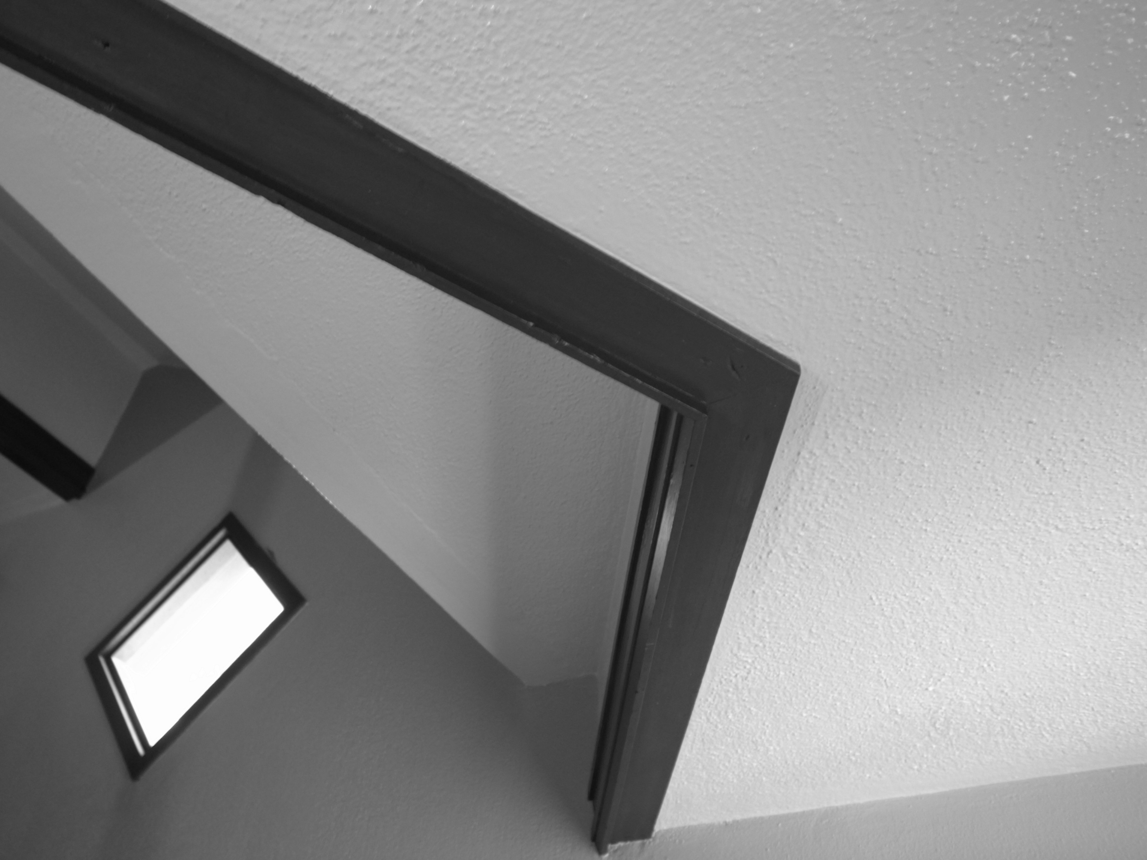 Black and white view of a ceiling and window frame from an angle