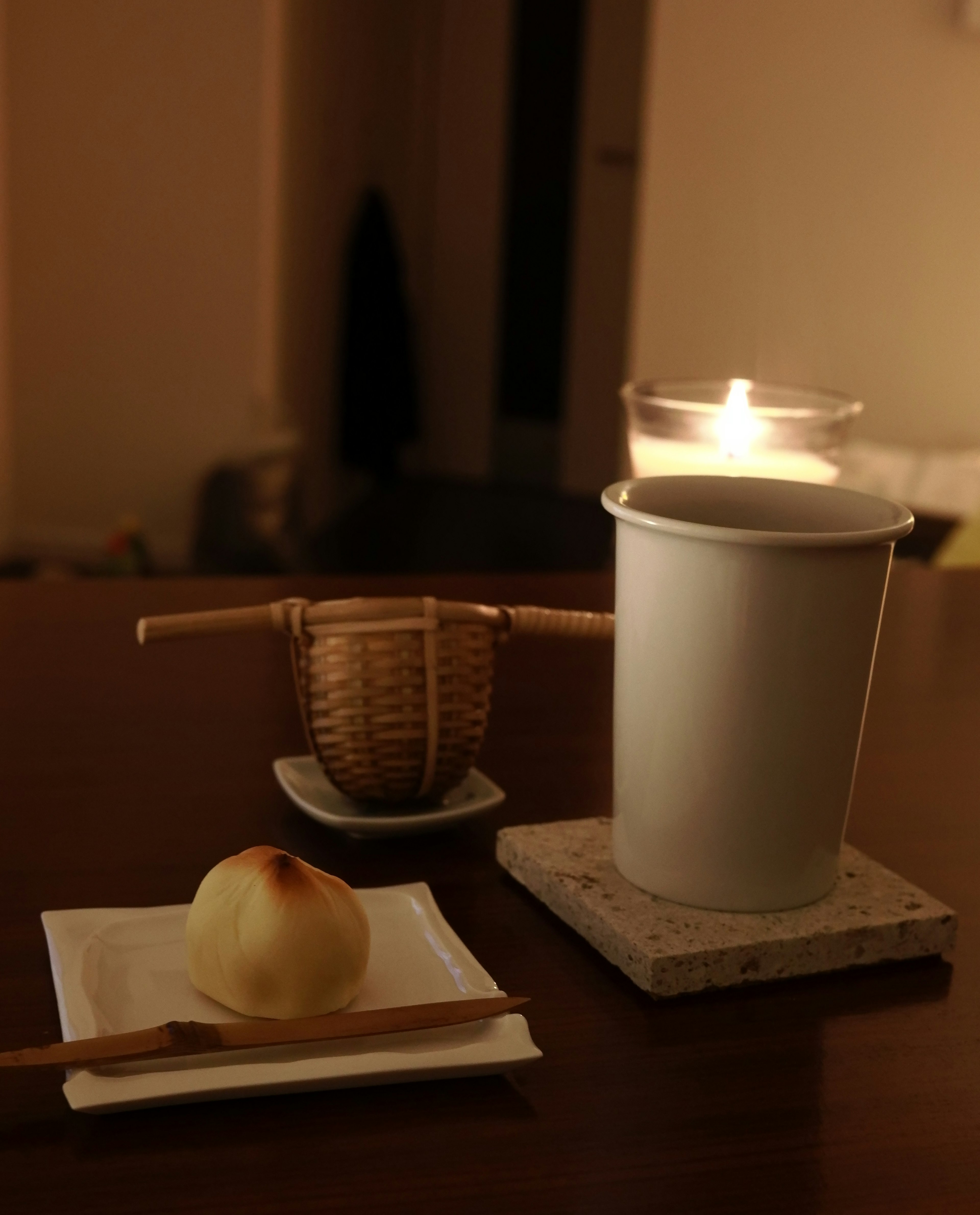 A simple and calming table setting featuring a candle, Japanese sweets, and tea utensils