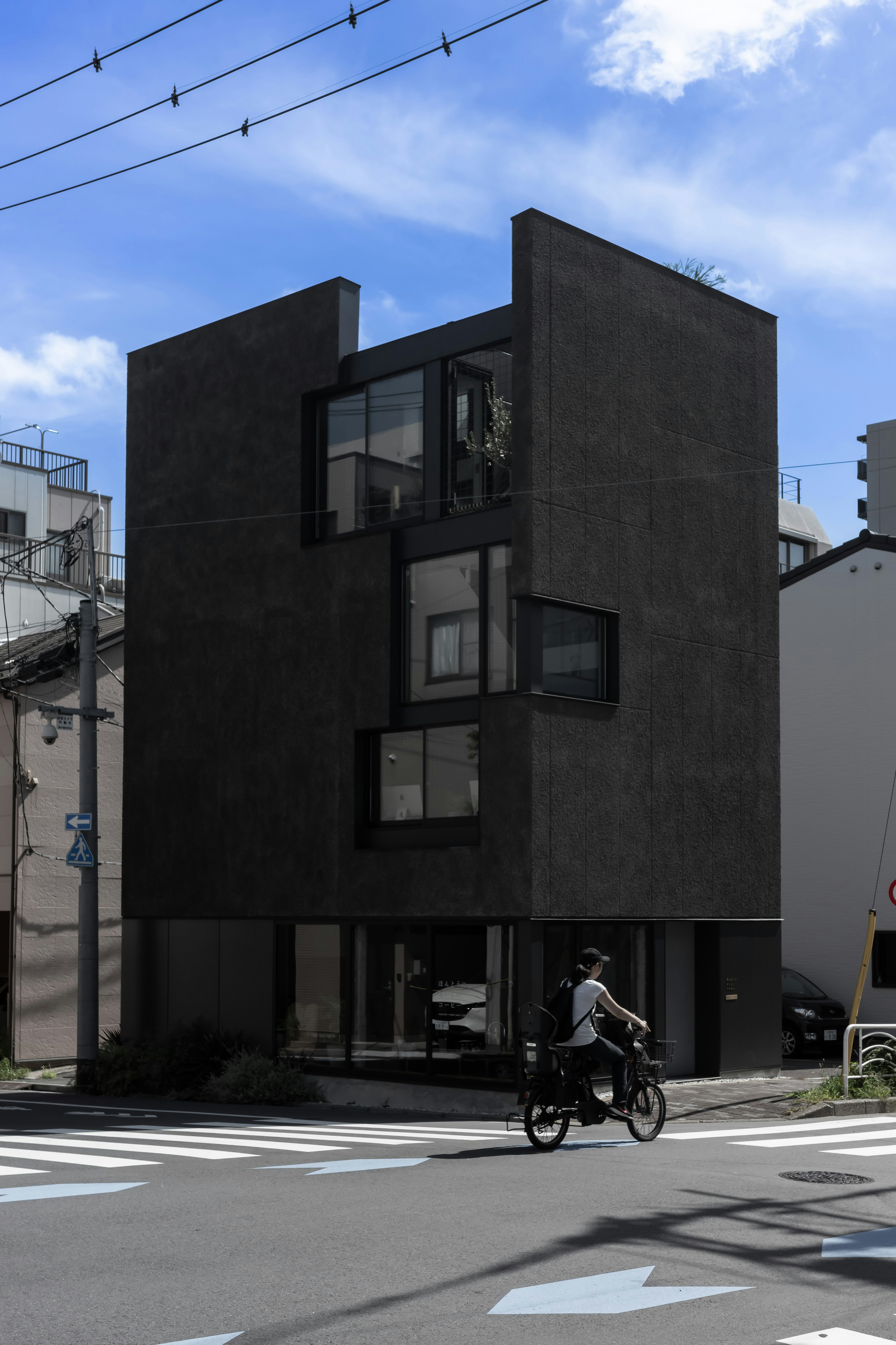 Modern black building with glass windows cyclist passing by