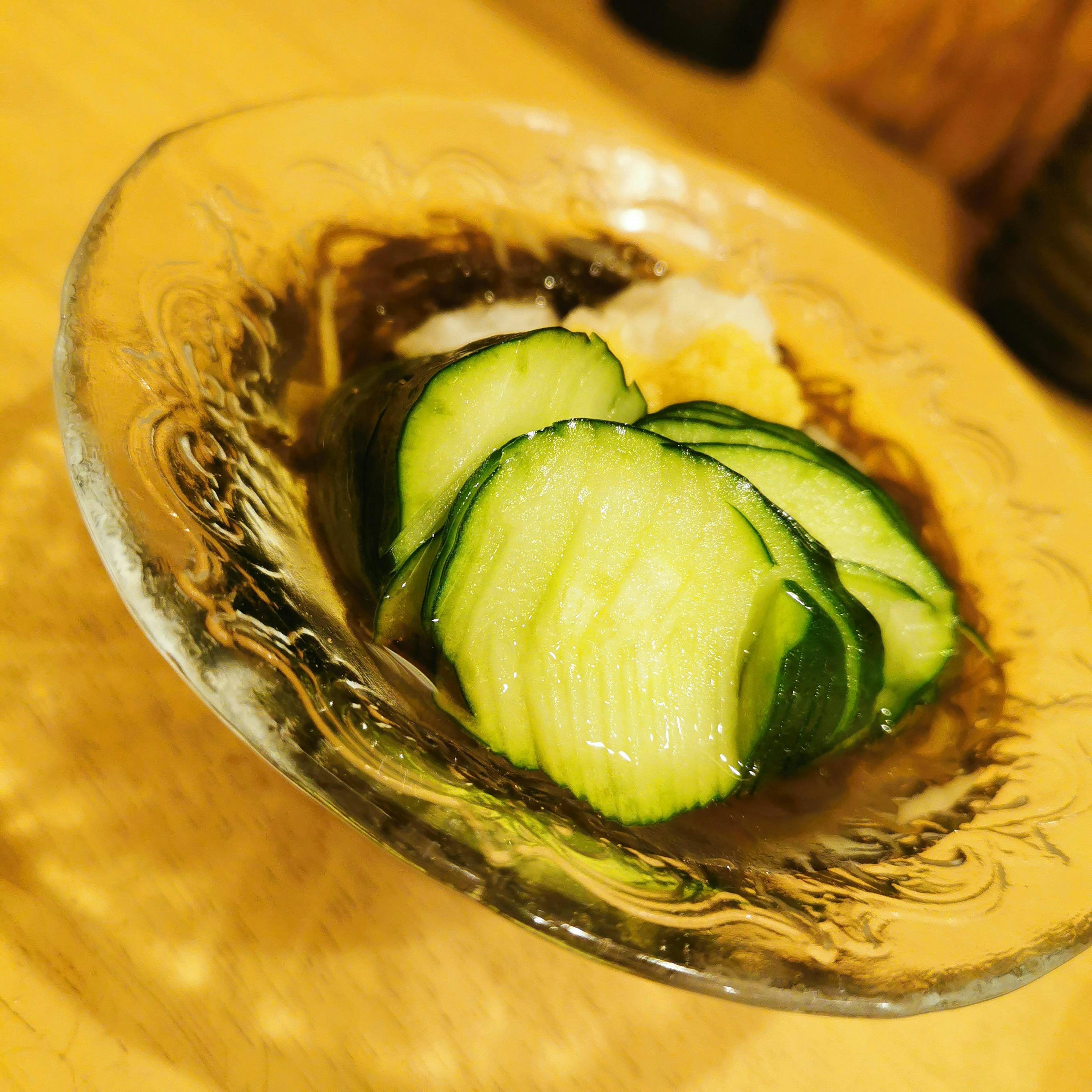 Ensalada japonesa con rodajas de pepino y un ingrediente blanco en un plato transparente