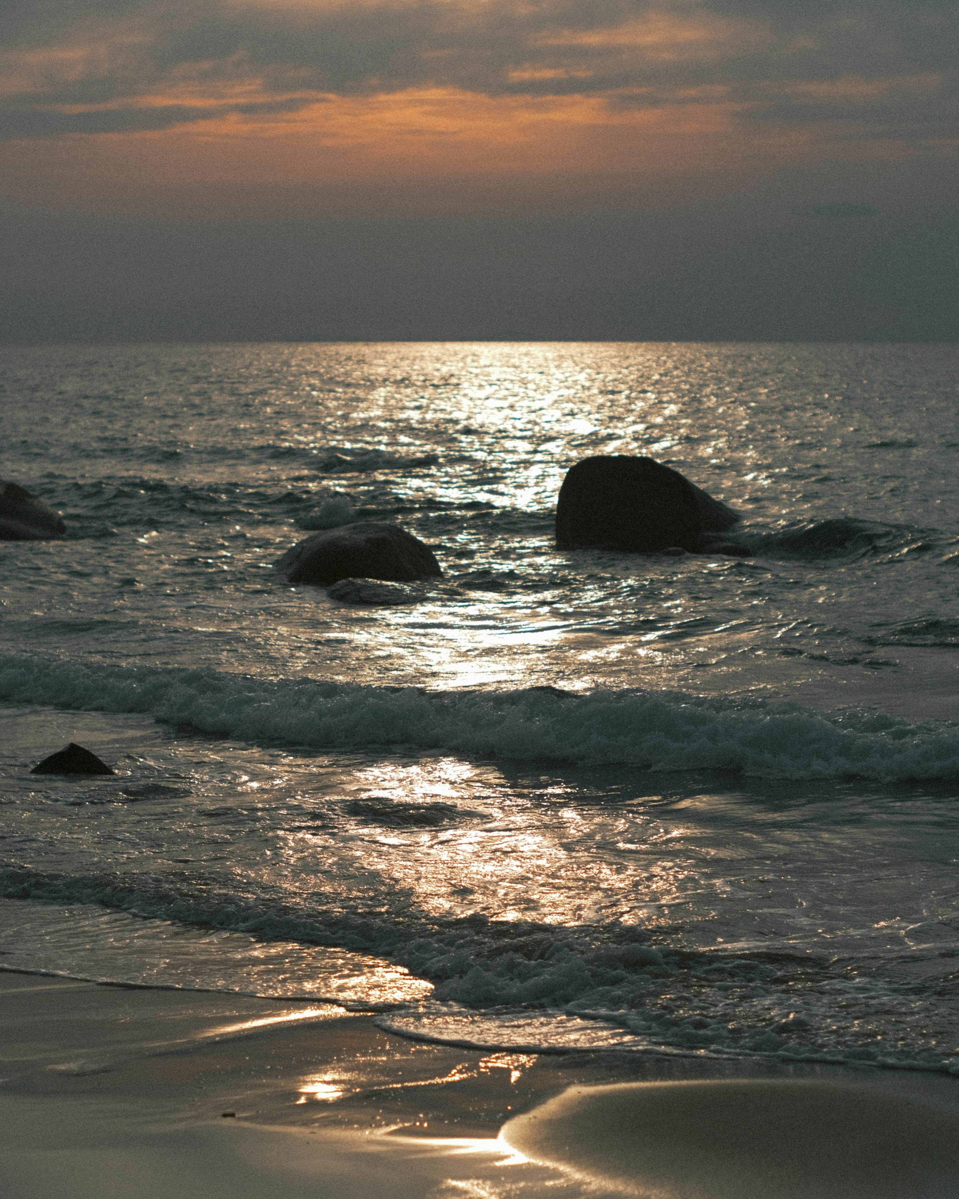 Tramonto sull'oceano con rocce e onde leggere