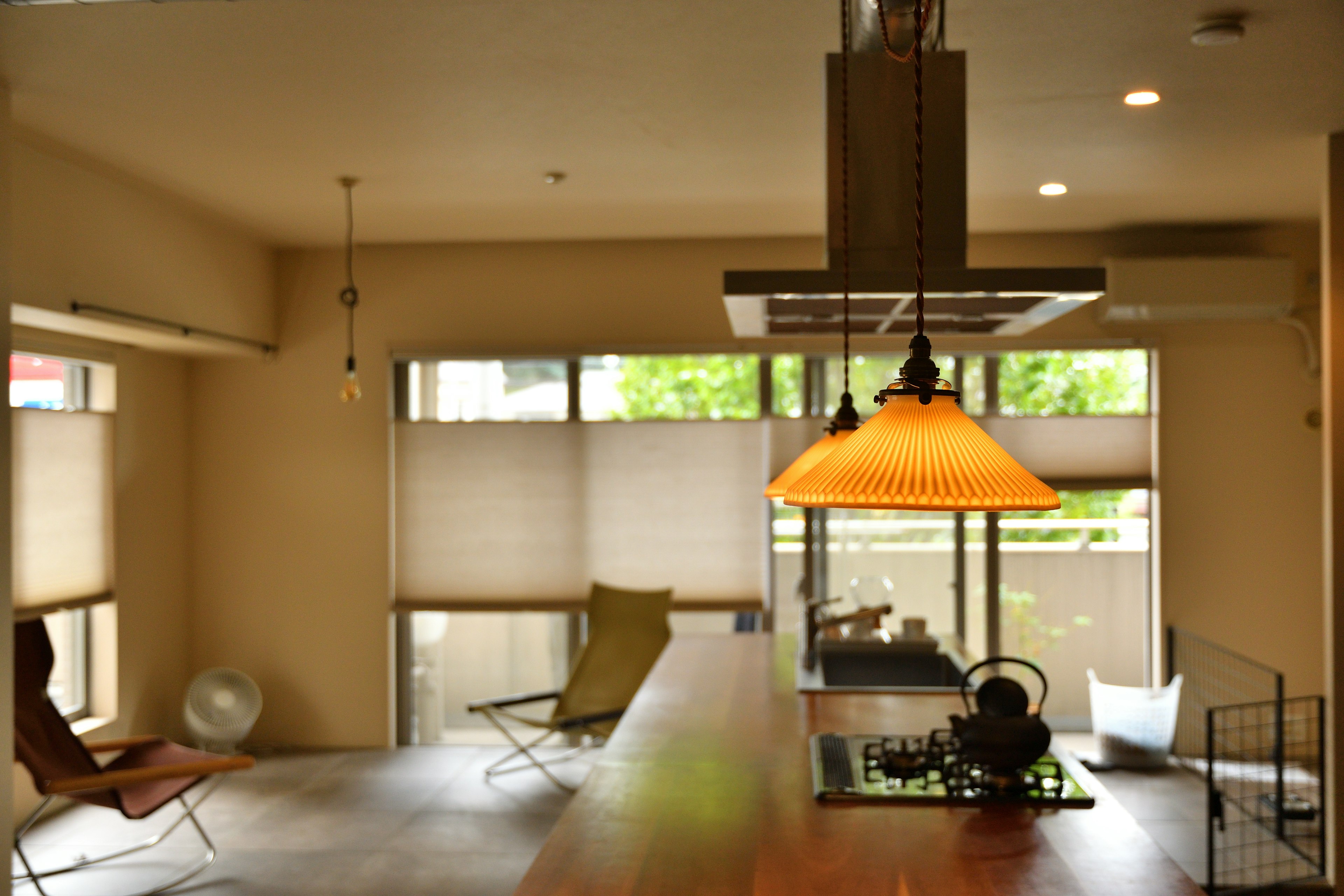 Sala de estar moderna y sencilla con mesa de madera lámpara colgante naranja y luz natural de las ventanas