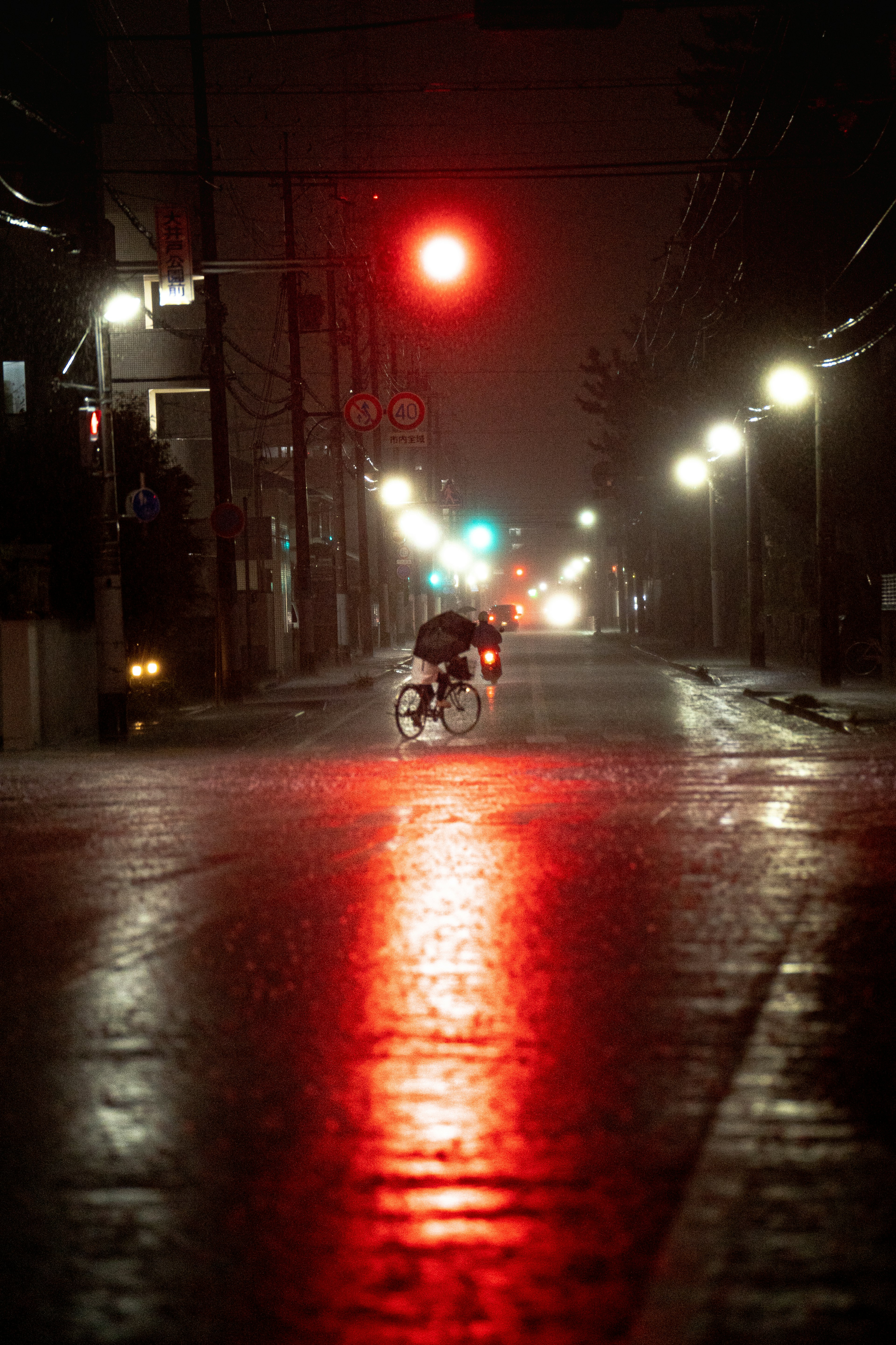 雨の夜の街並み 赤信号と青信号の交差点 バイクが走る