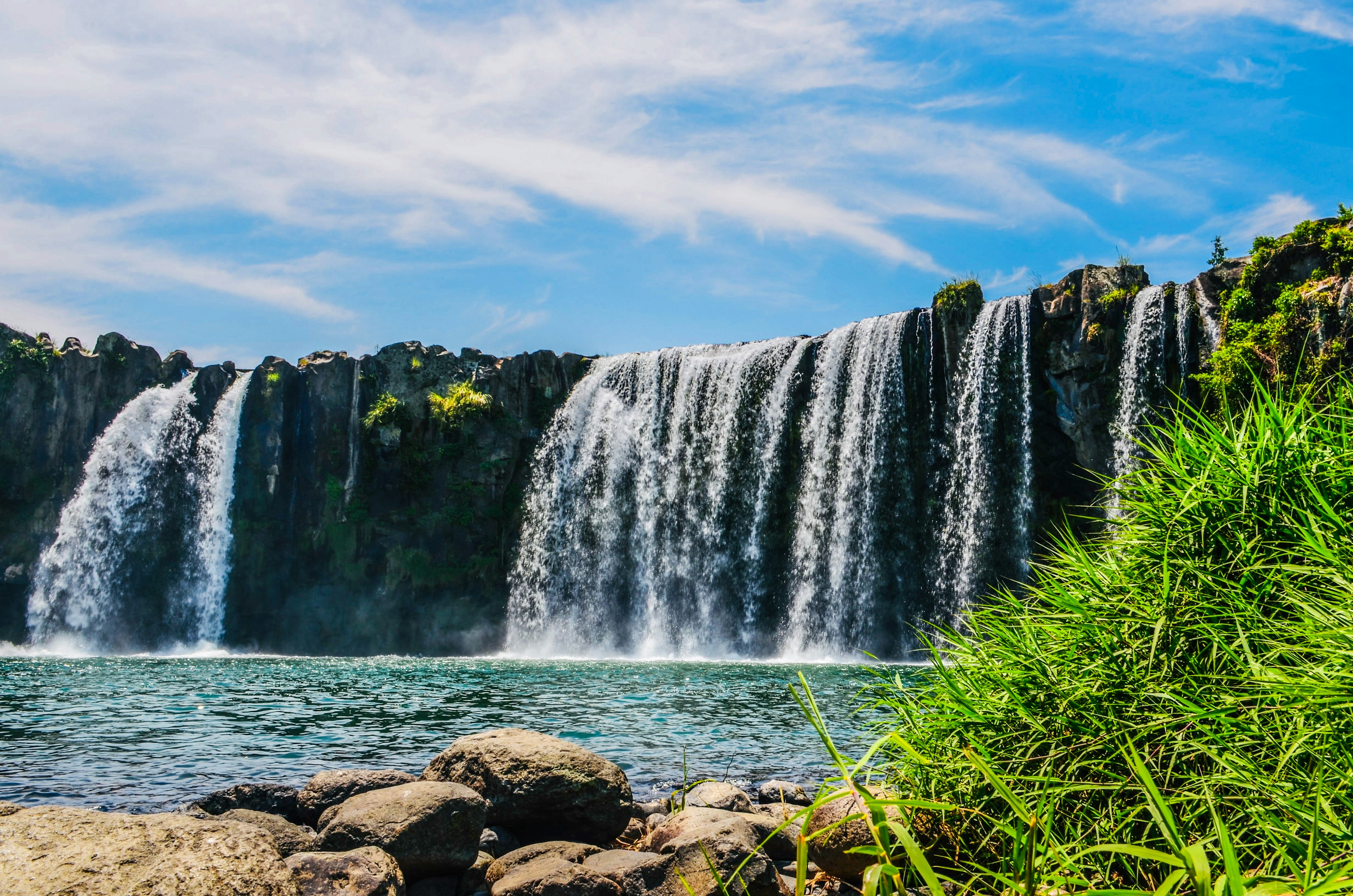 Bellissimo paesaggio con cascate circondate da erba verde e rocce