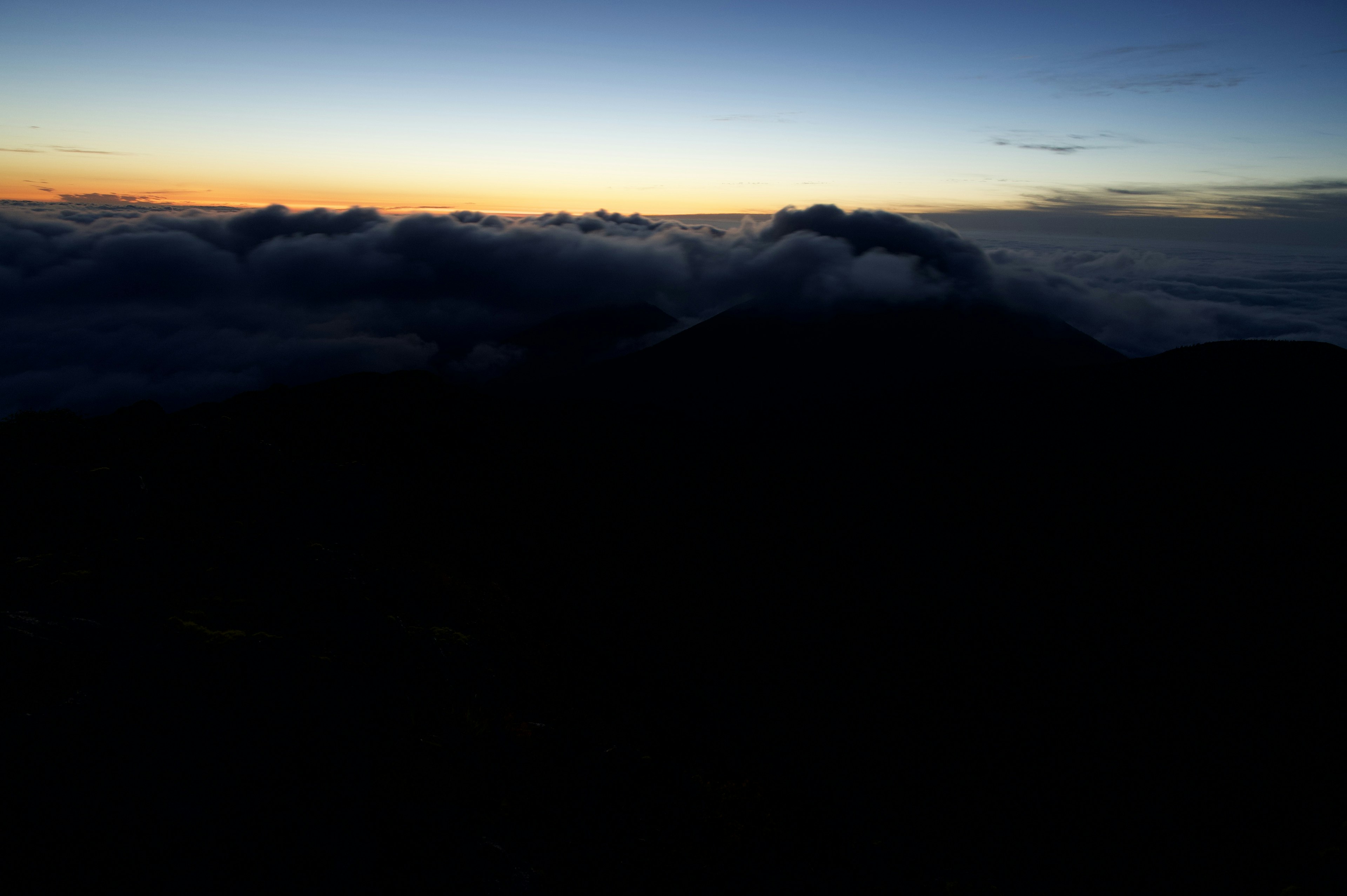 山の上からの夜明けの景色雲の間から見えるオレンジ色の空