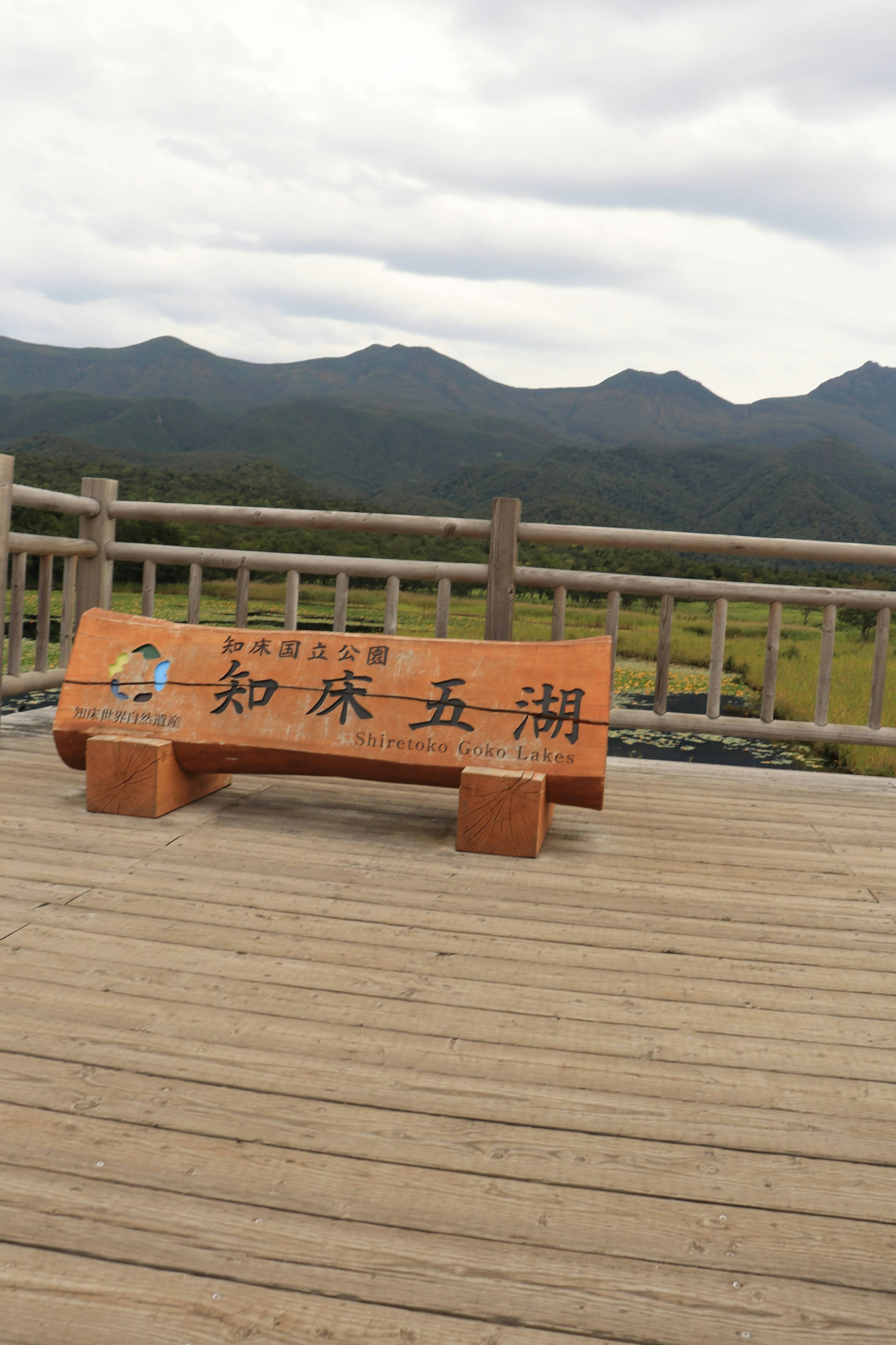 Wooden bench with a sign set against a mountainous landscape