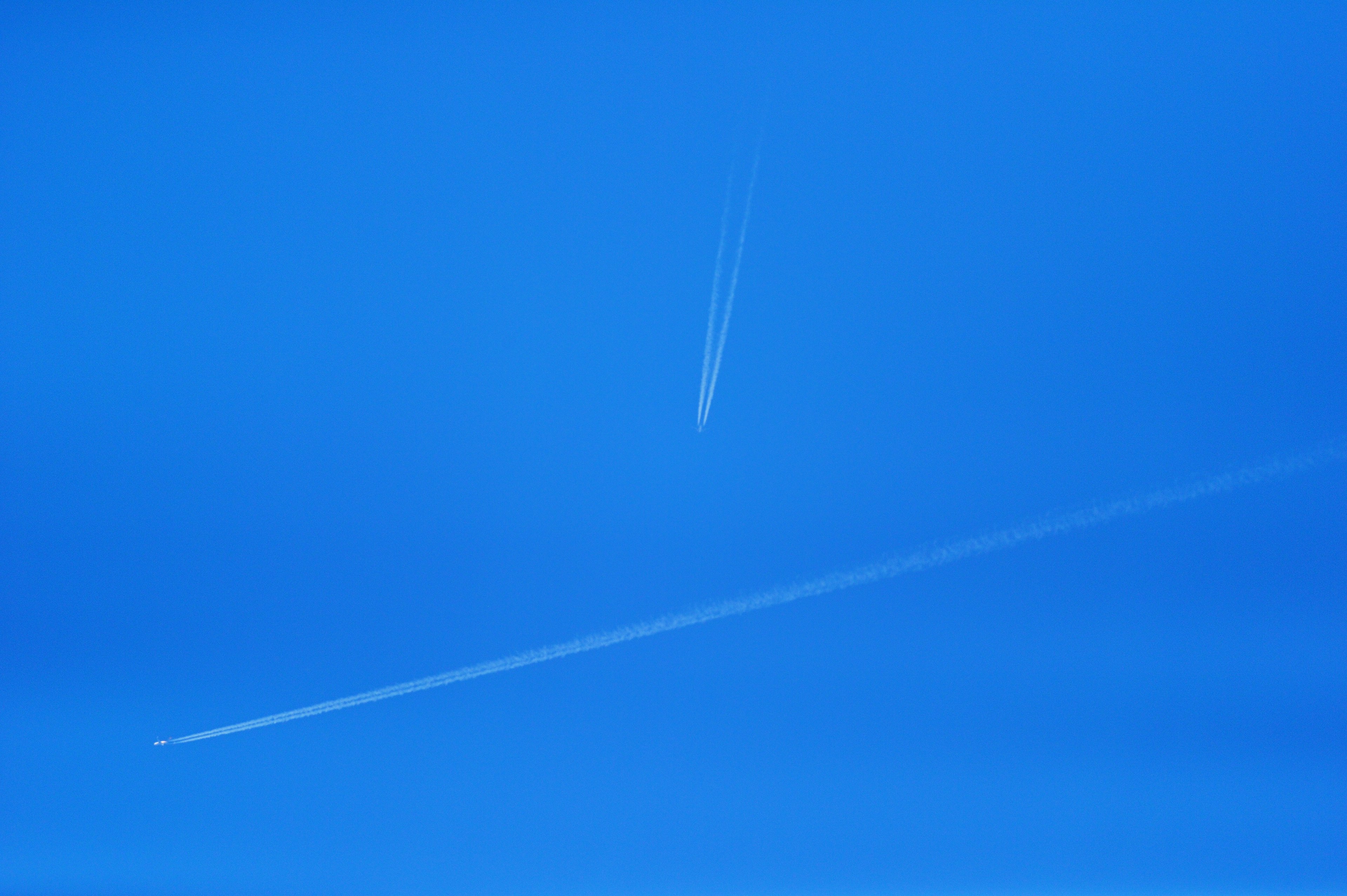 Dua jejak pesawat terlihat di langit biru