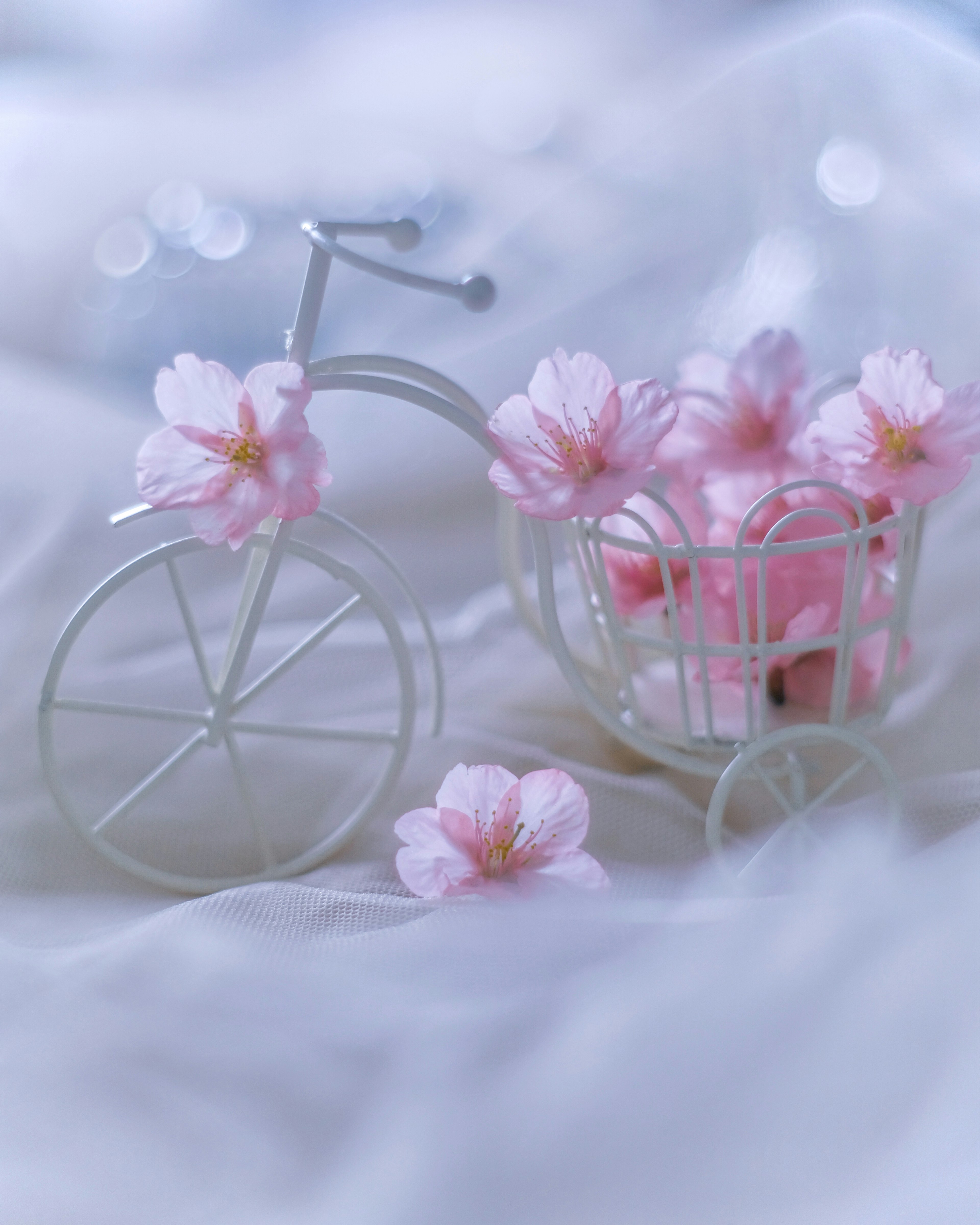 A small white bicycle adorned with pink flowers in a soft setting