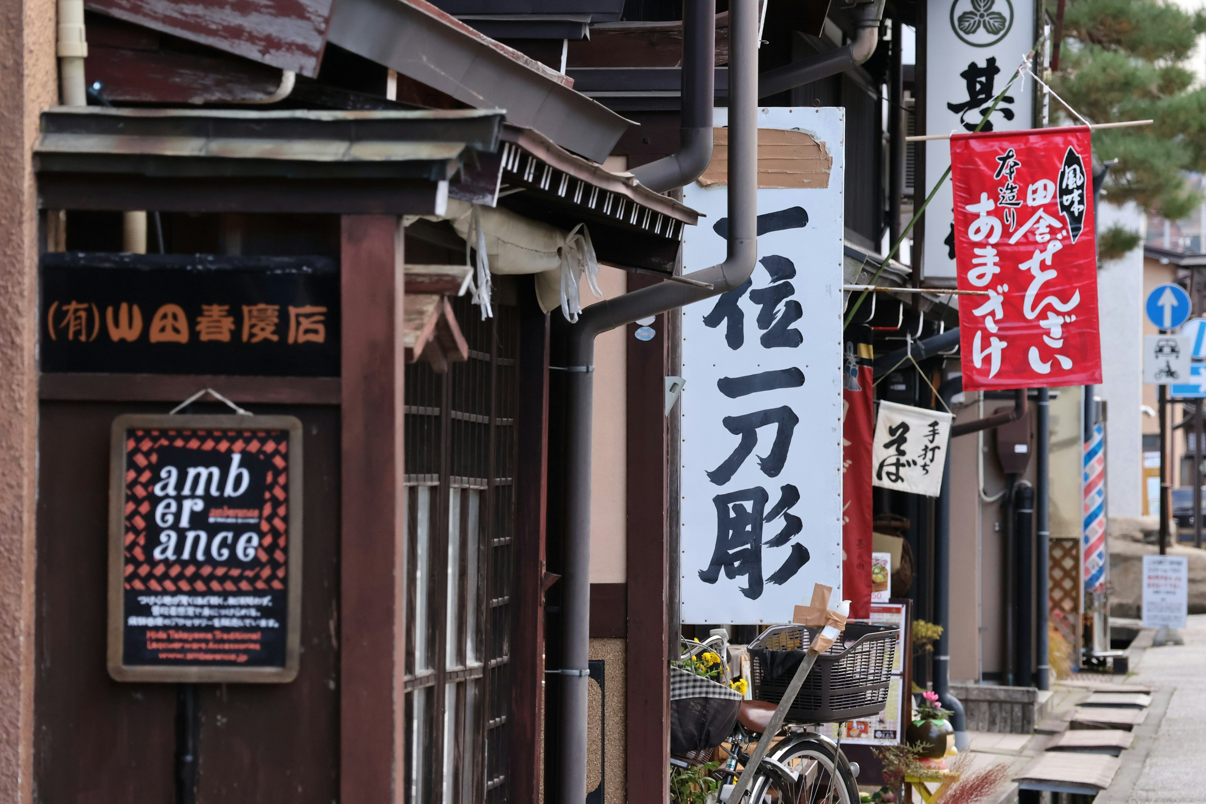 Vista de una calle comercial japonesa tradicional con letreros y una bicicleta