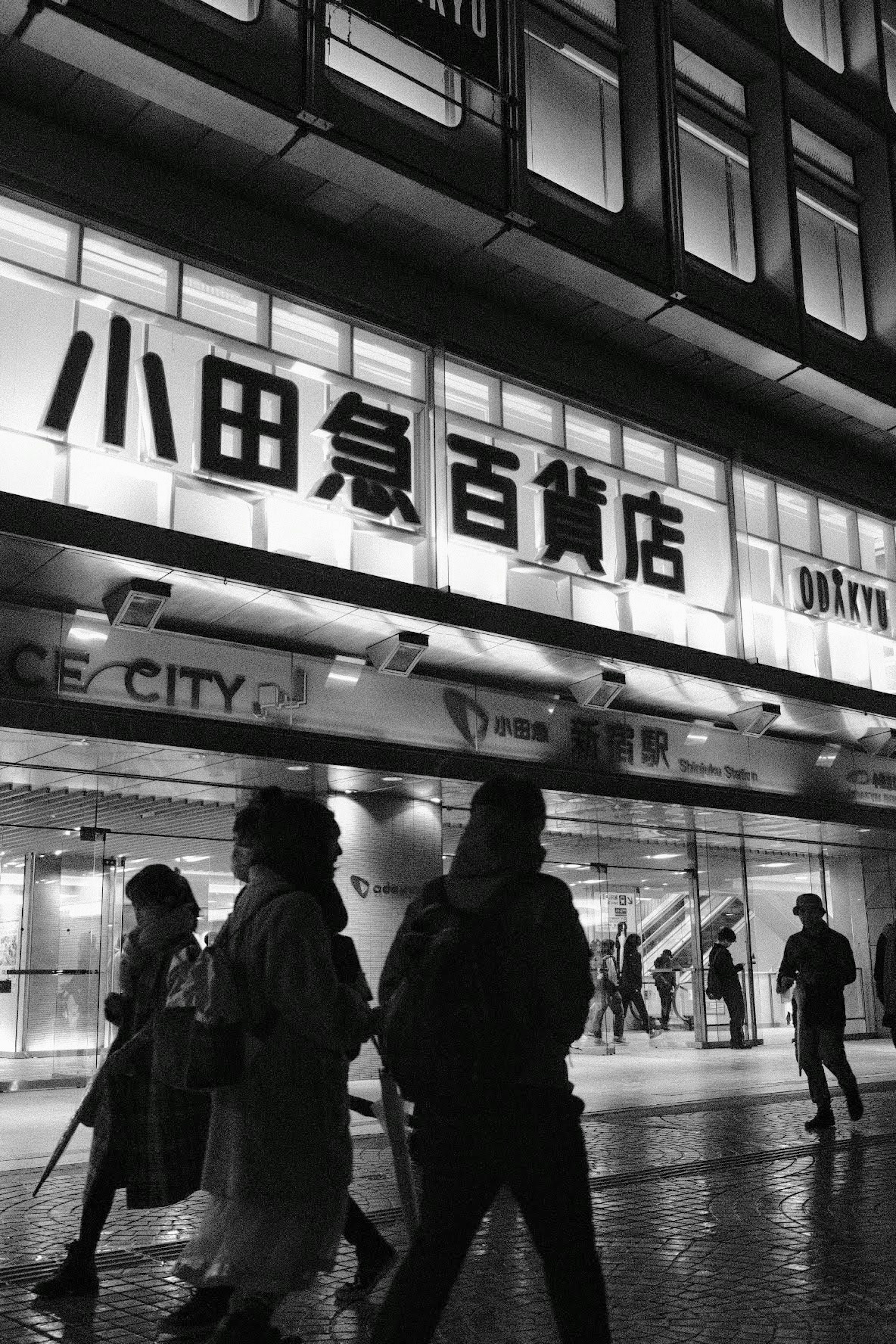 Des personnes marchant devant le magasin Odakyu la nuit