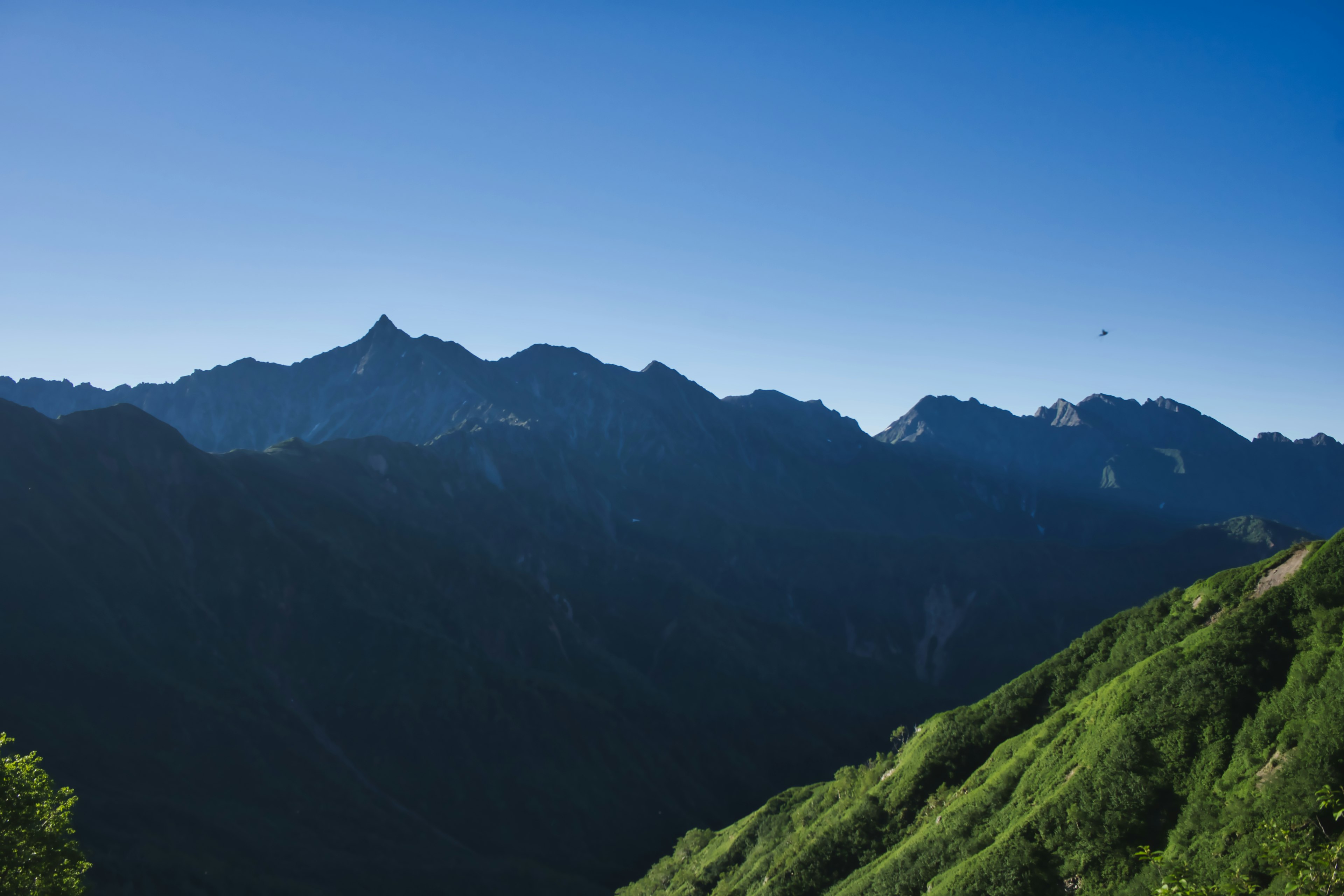 Malersicher Blick auf grüne Berge unter klarem blauen Himmel