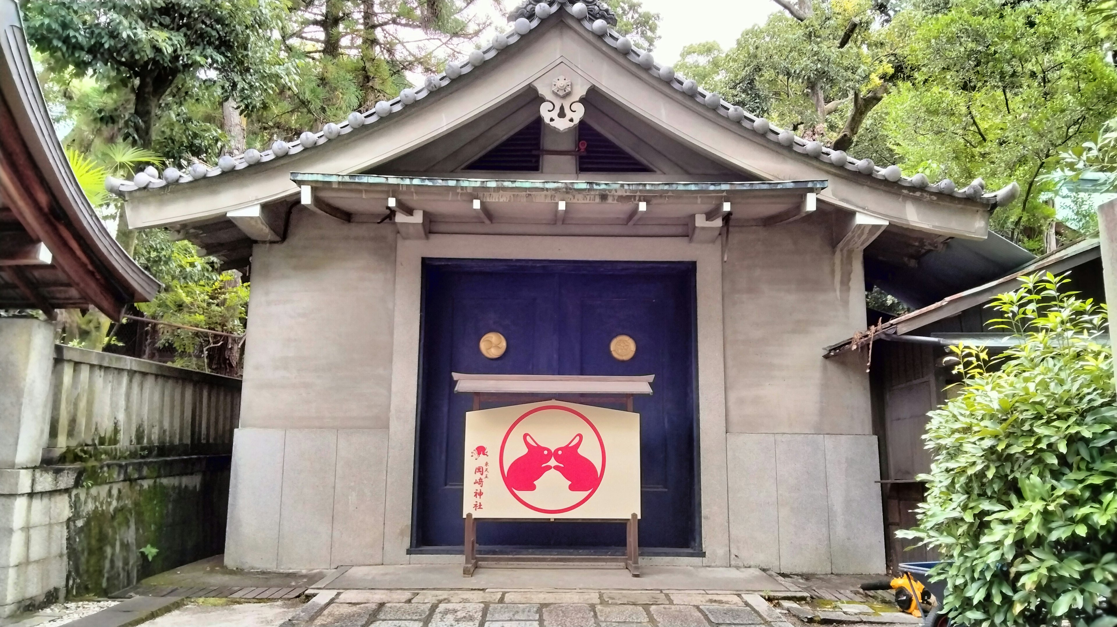 Exterior de un edificio japonés tradicional con una puerta azul y una pancarta con un emblema rojo