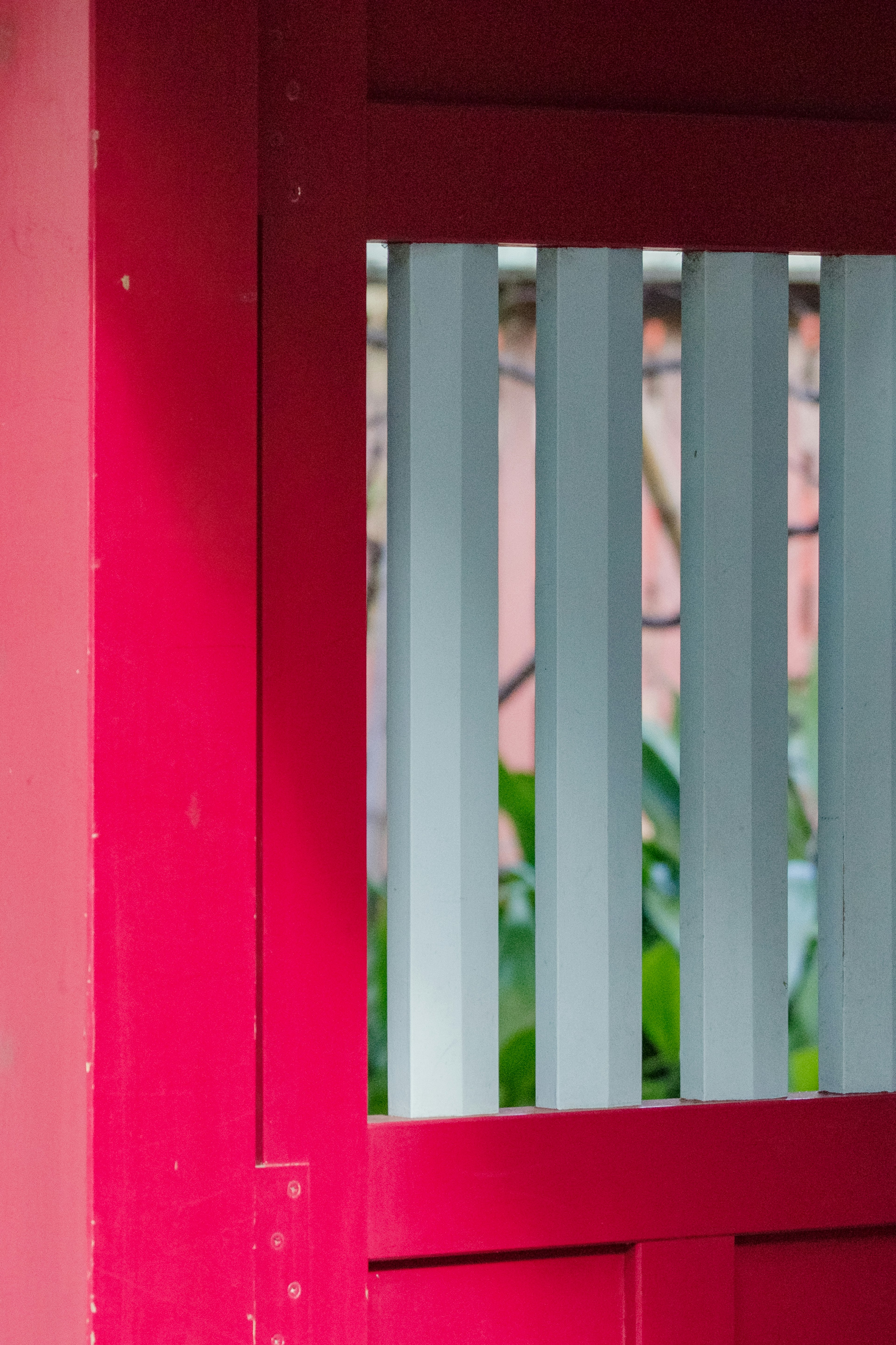 Vista parcial de una puerta roja con listones blancos verticales