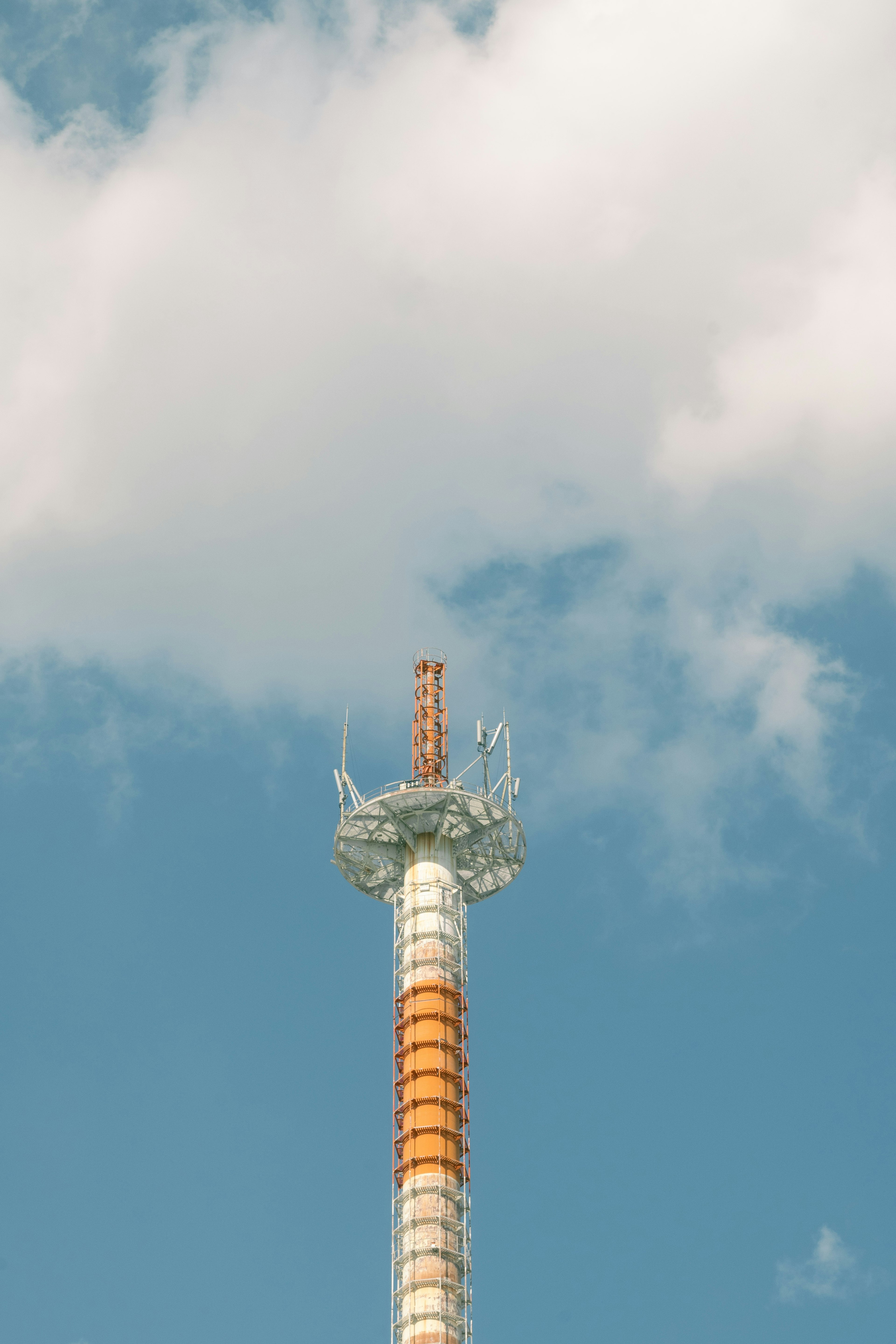 Communication tower with orange and white stripes against a blue sky