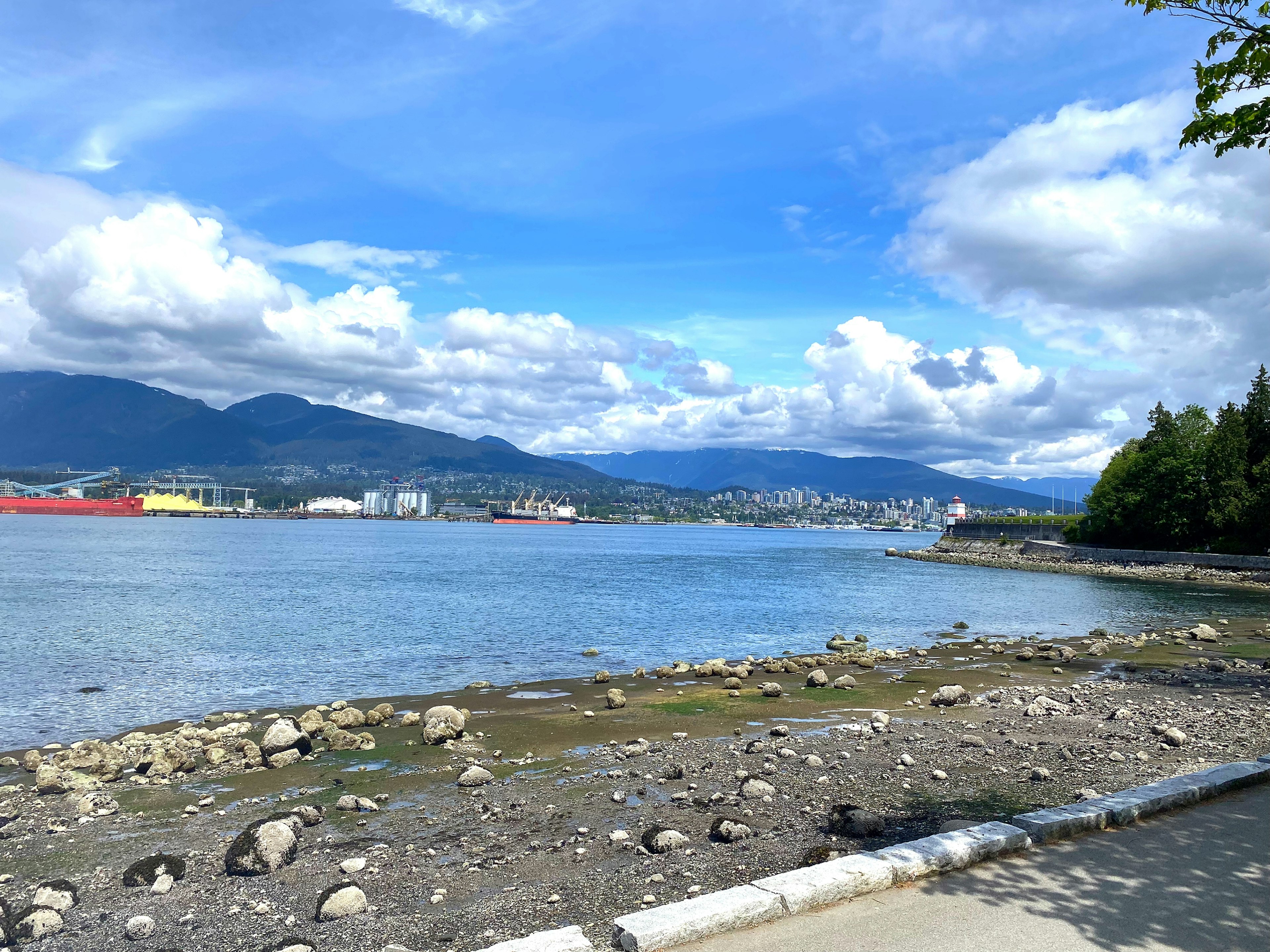 Pemandangan pantai yang indah dengan langit biru dan awan putih menampilkan garis pantai berbatu dan berpasir