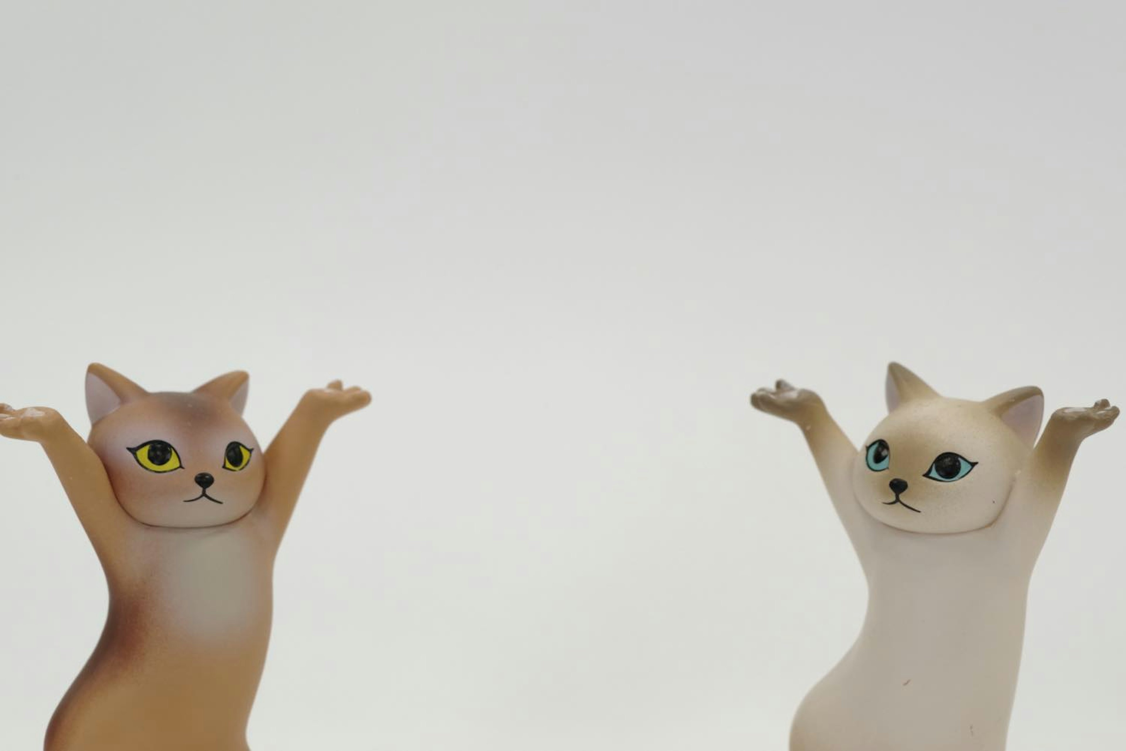 Two cat figurines with raised arms