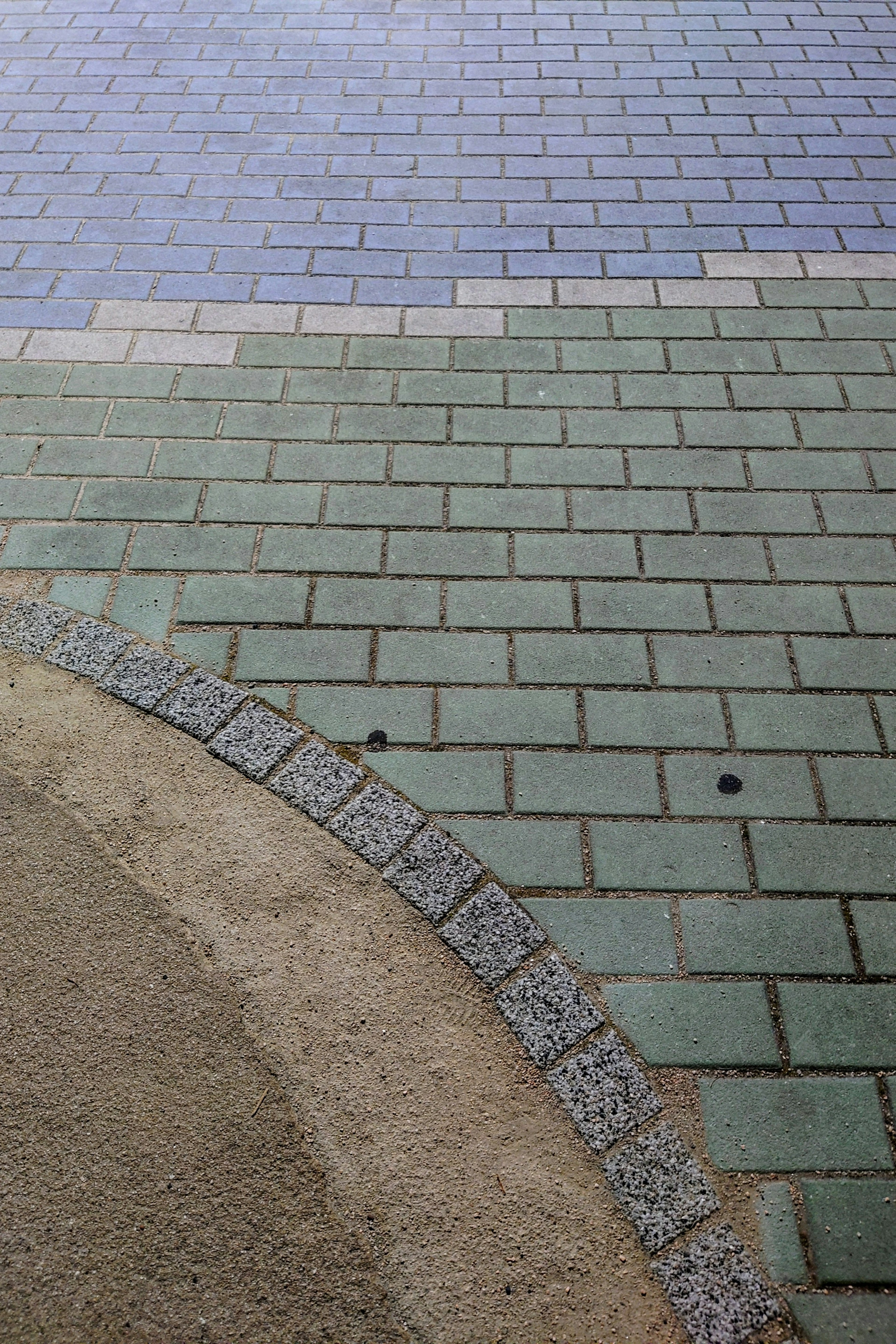 Pattern of green and blue tiles intersecting on pavement