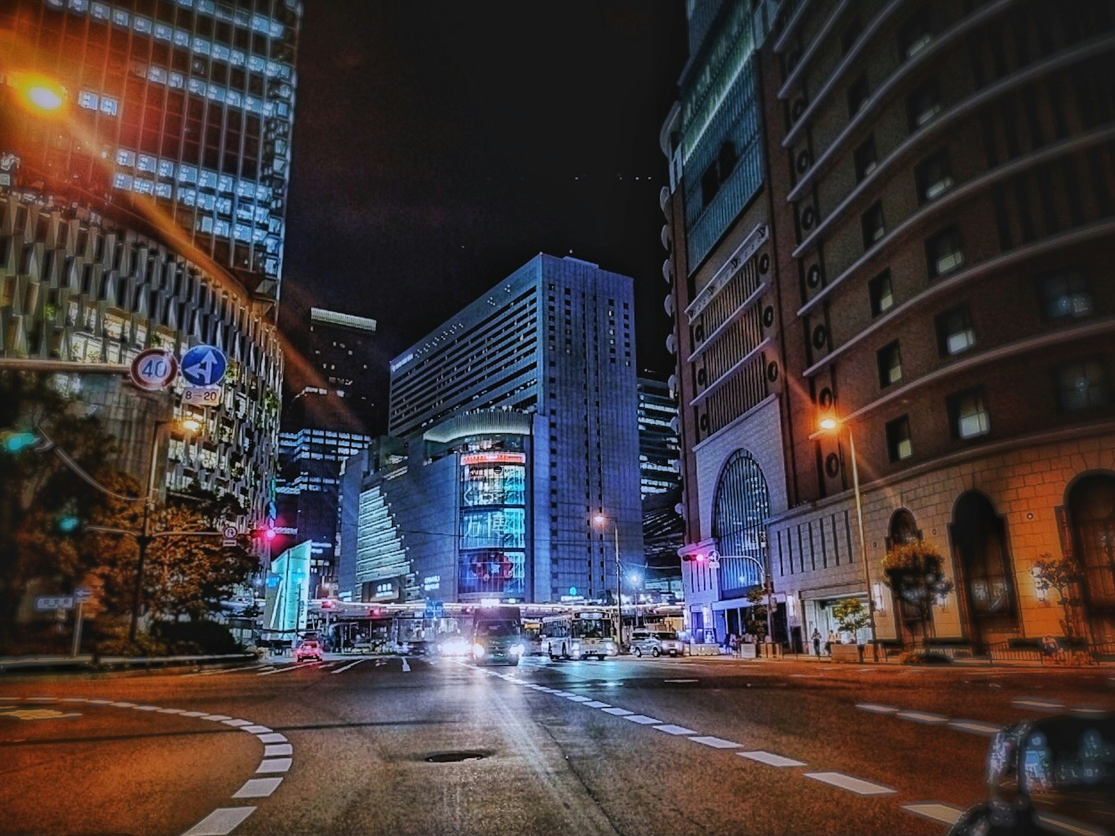 Paysage urbain nocturne avec de grands bâtiments et des voitures à un carrefour