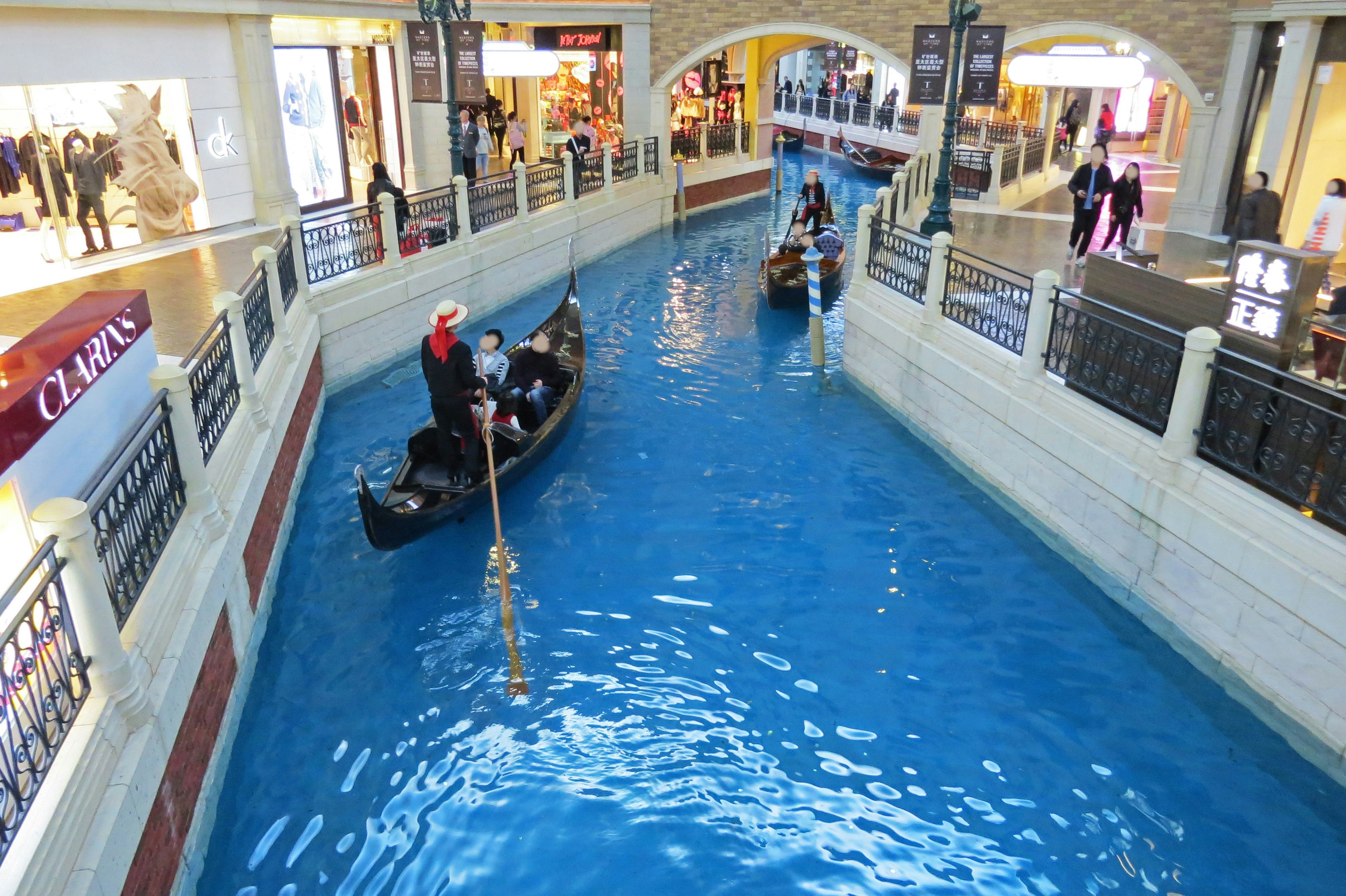 People riding gondolas in a canal inside a shopping mall