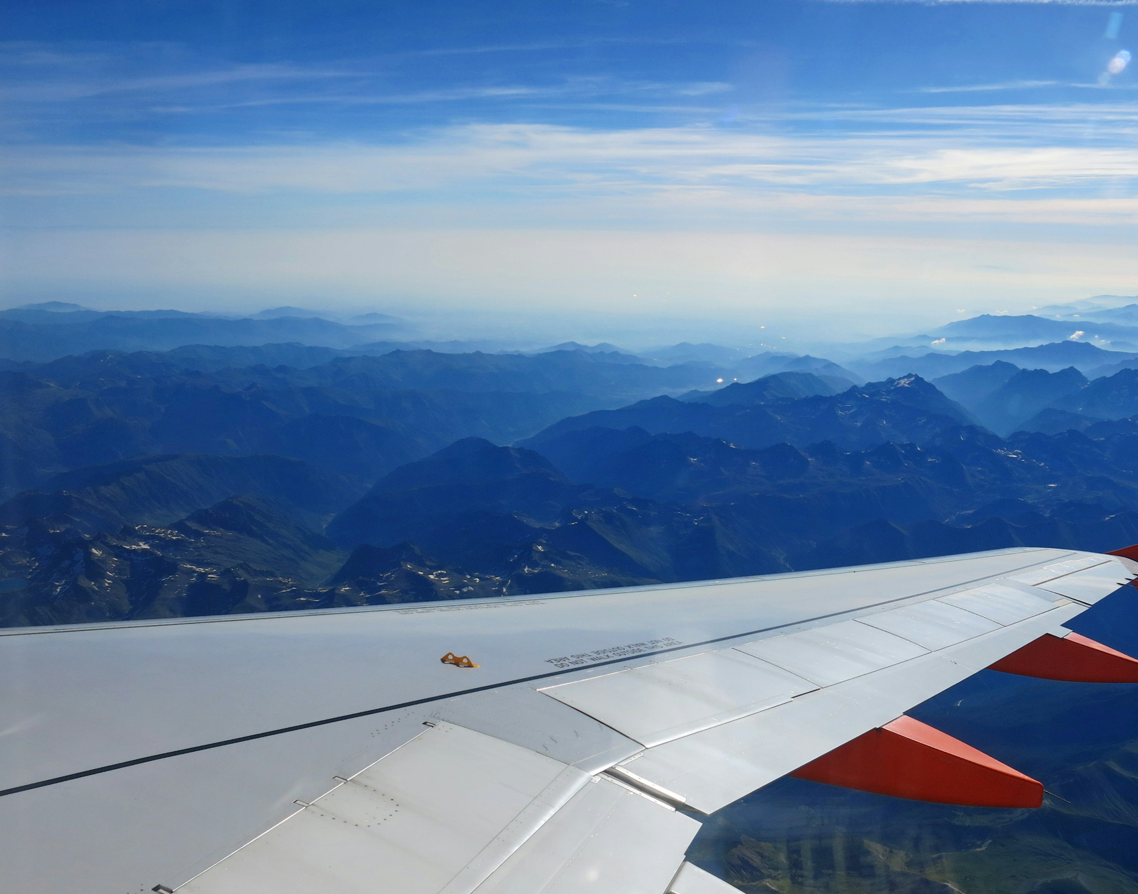 Airplane wing overlooking blue sky and mountainous landscape