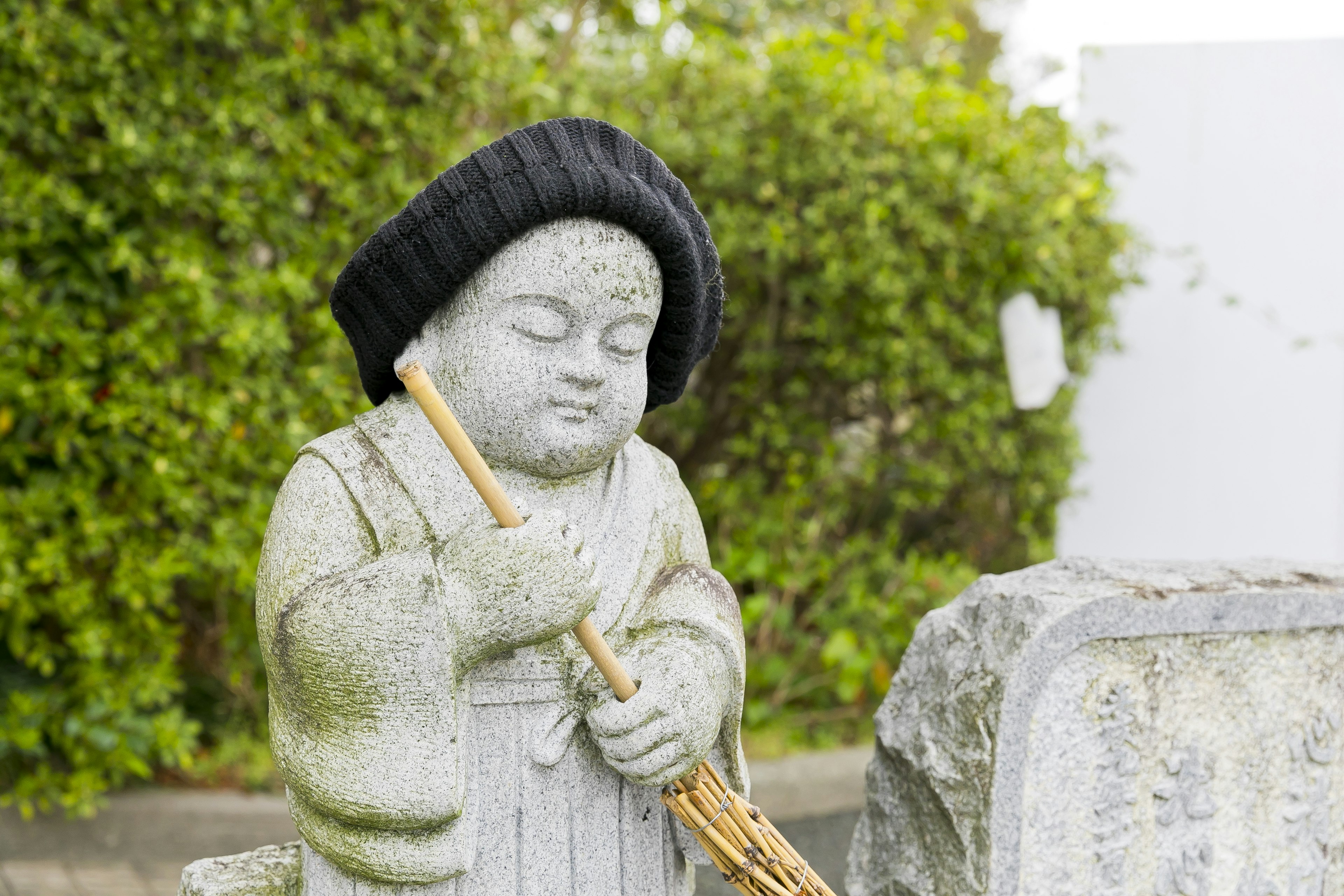 Estatua de piedra de un niño sosteniendo una flauta y usando un sombrero