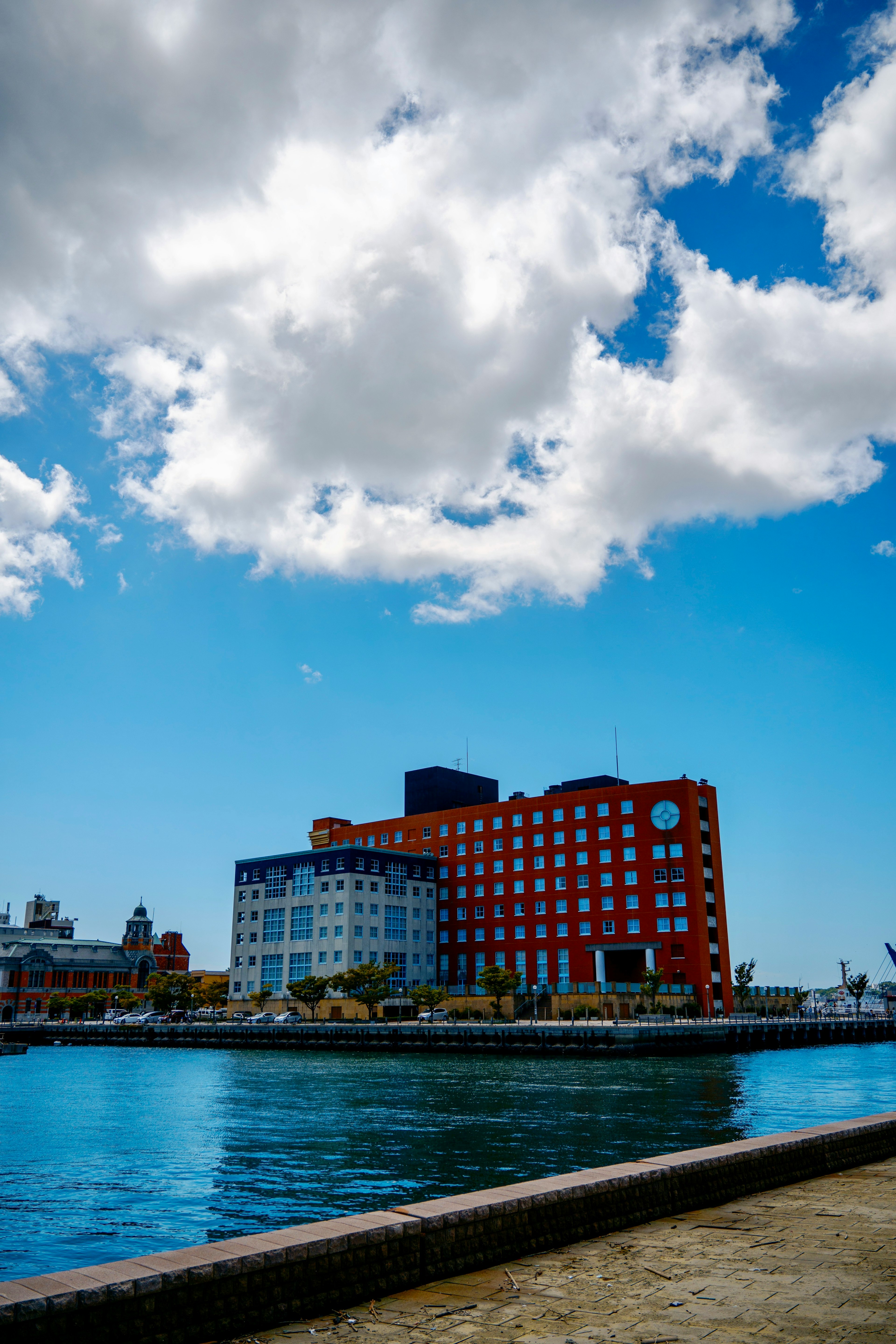 Bâtiment rouge au bord de l'eau sous un ciel bleu avec des nuages blancs