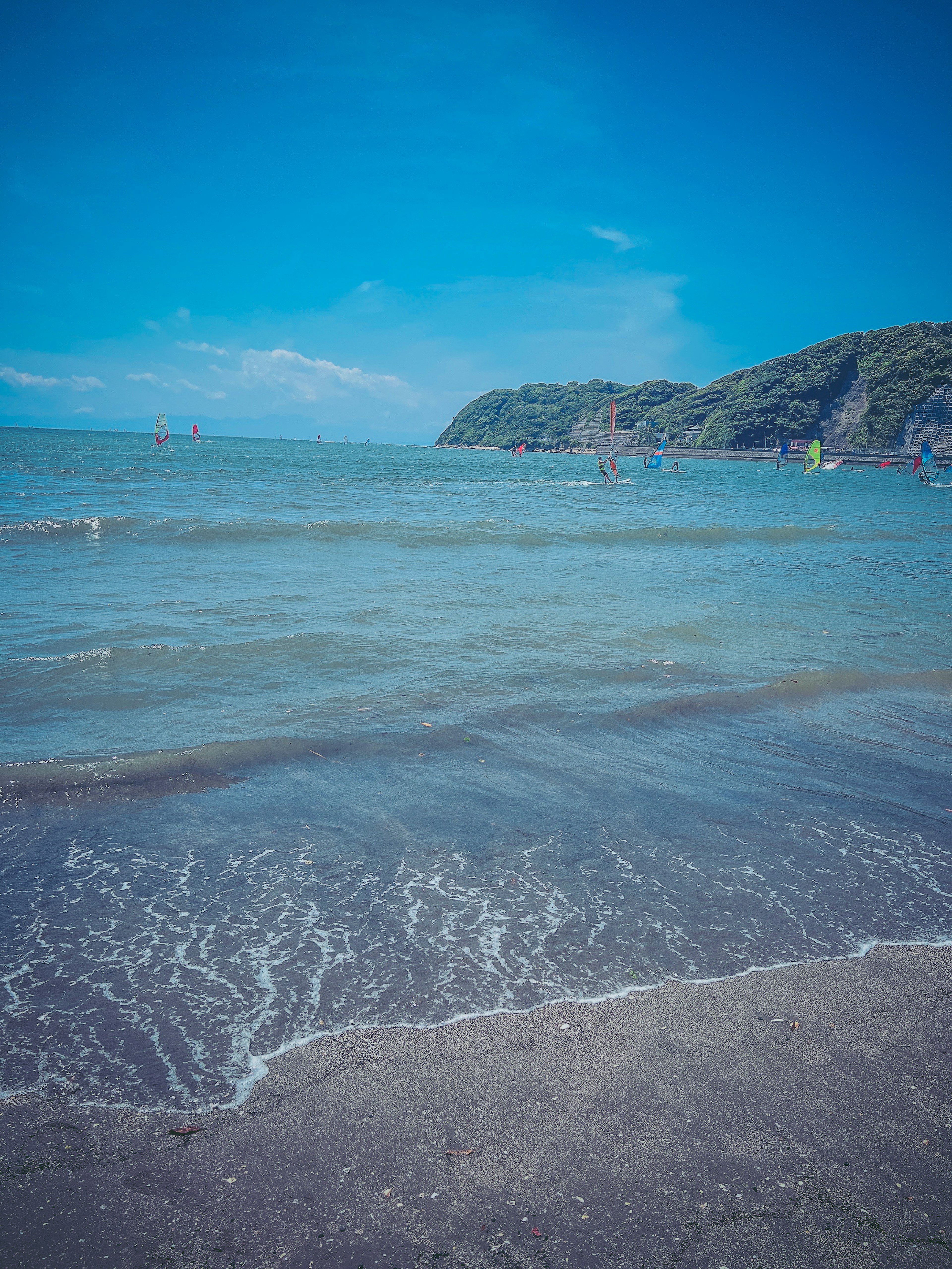 ทิวทัศน์ชายหาดที่มีมหาสมุทรสีน้ำเงินและคลื่นที่นุ่มนวล