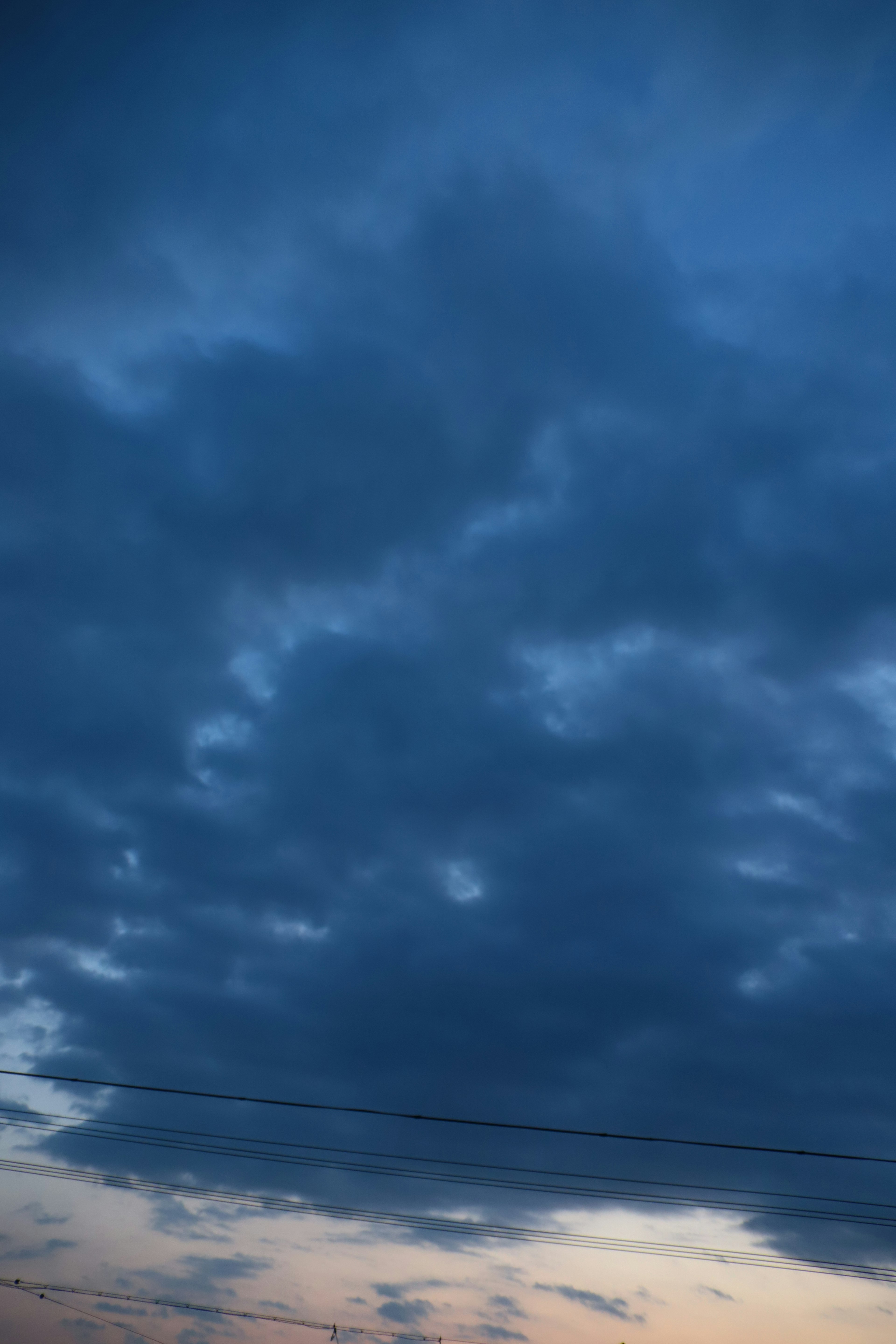 Dark clouds in a blue sky with hints of orange sunset