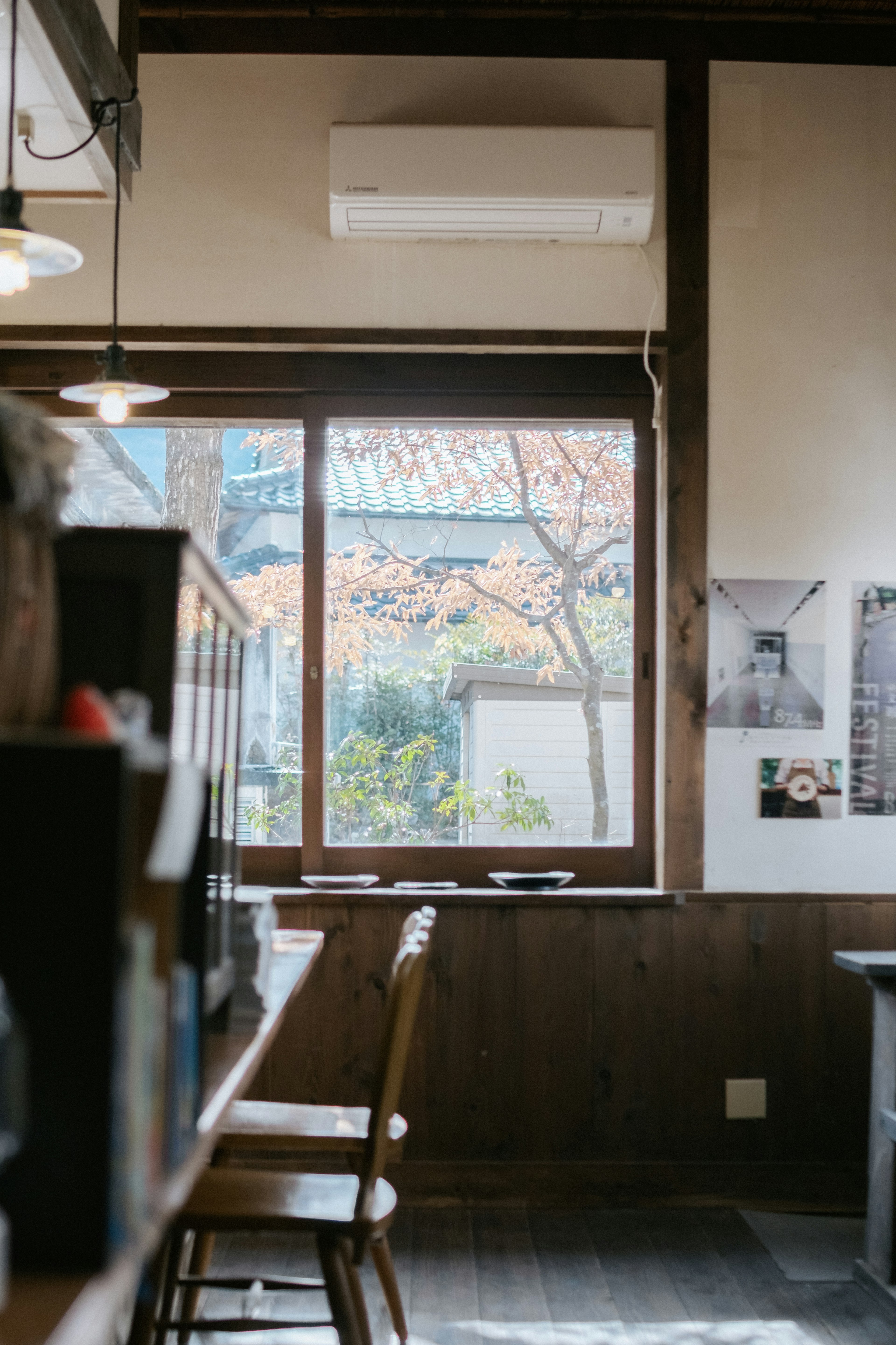 Vista interior de una cafetería con sillas de madera y una ventana